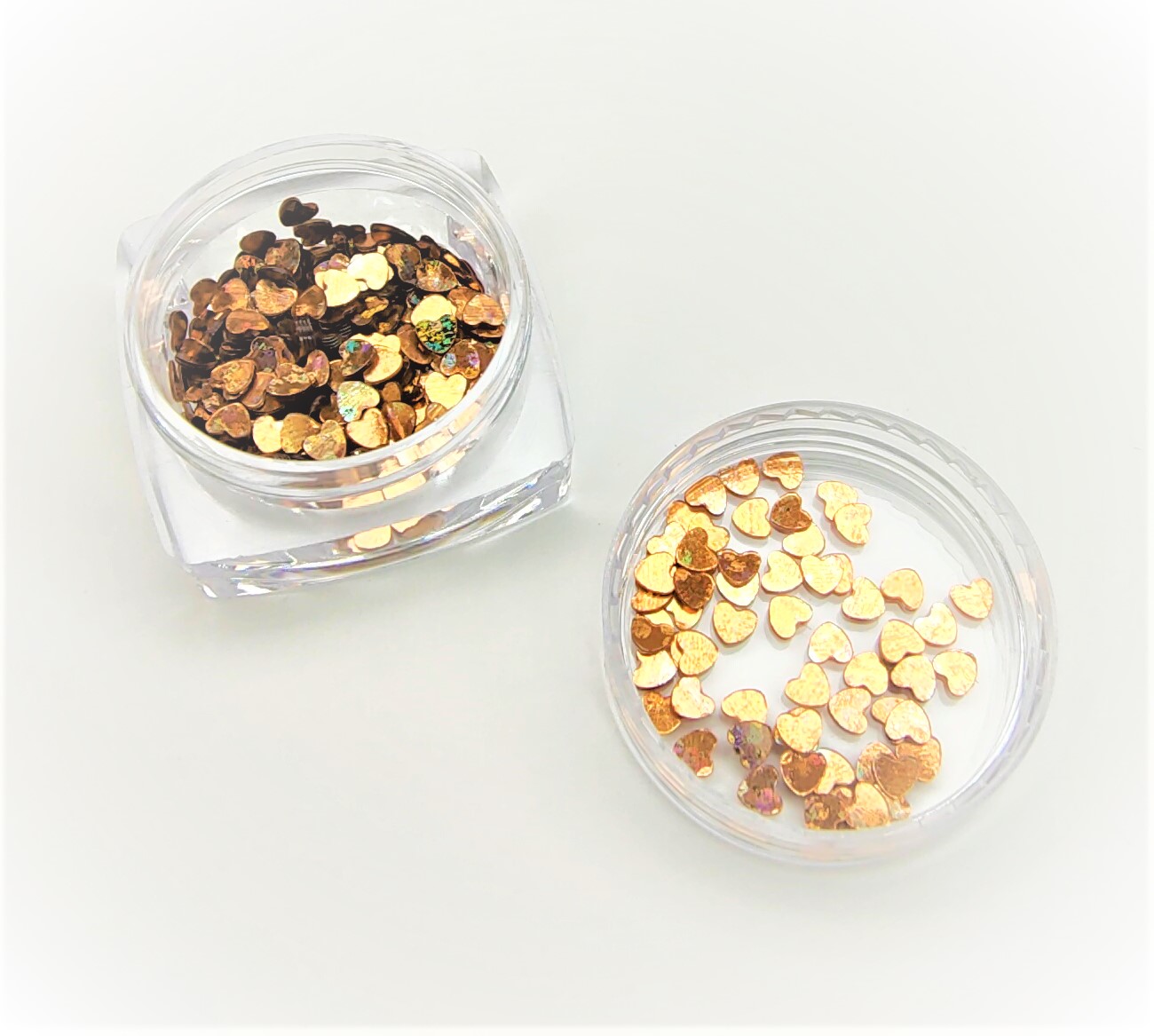 Frasco transparente com pequenos corações metálicos dourados e tampa separada