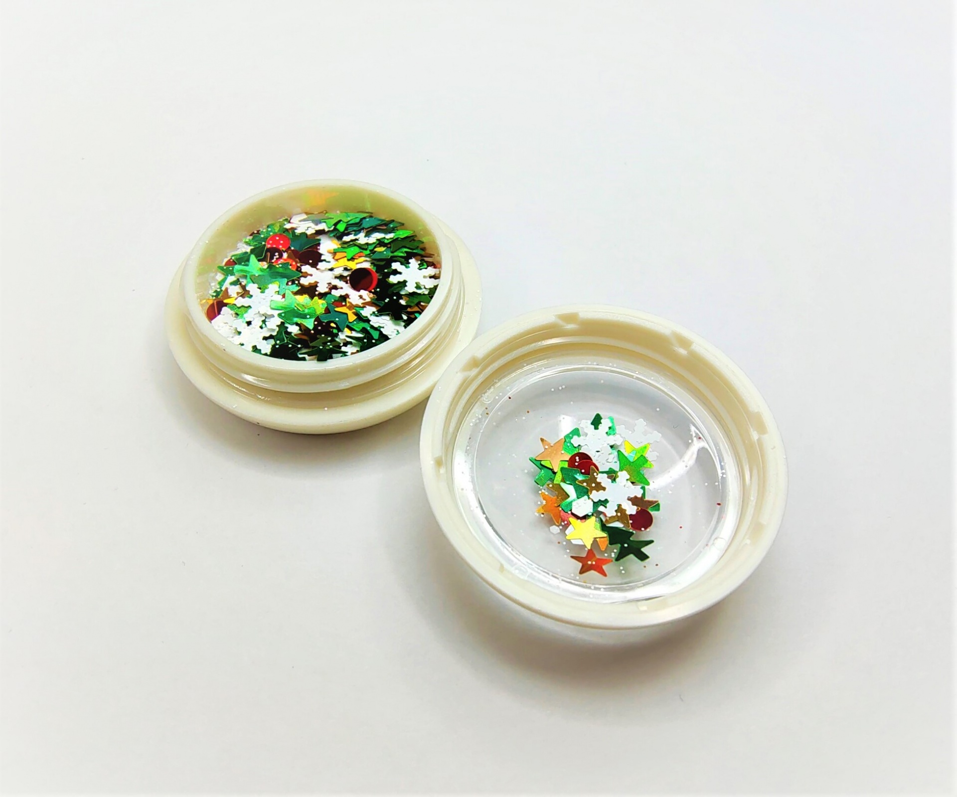 Duas tampas plásticas brancas com confetes coloridos em forma de estrelas e flocos de neve