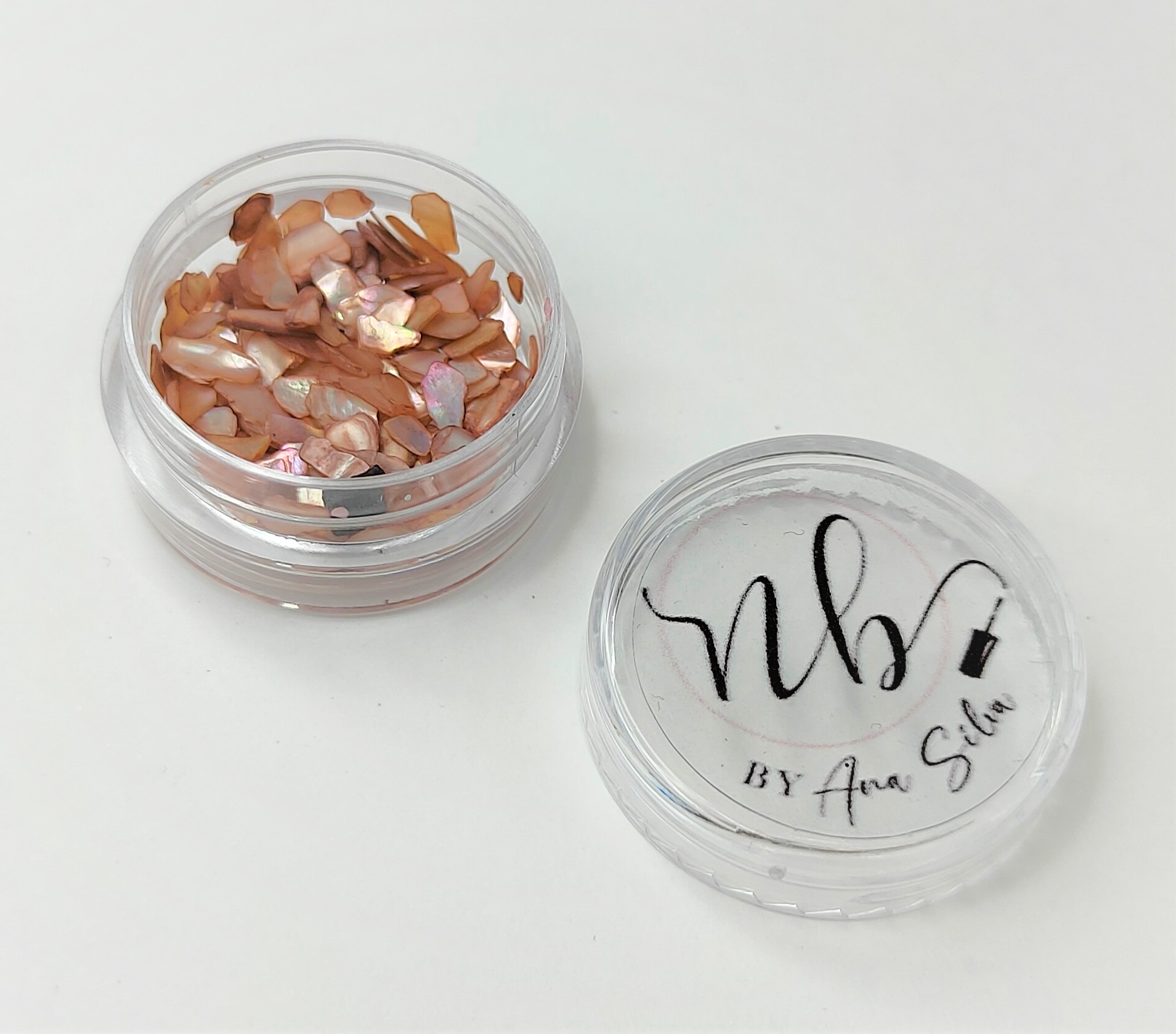Recipiente transparente com pedaços de conchas castanhas e tampa com texto nb BY Ana Silva