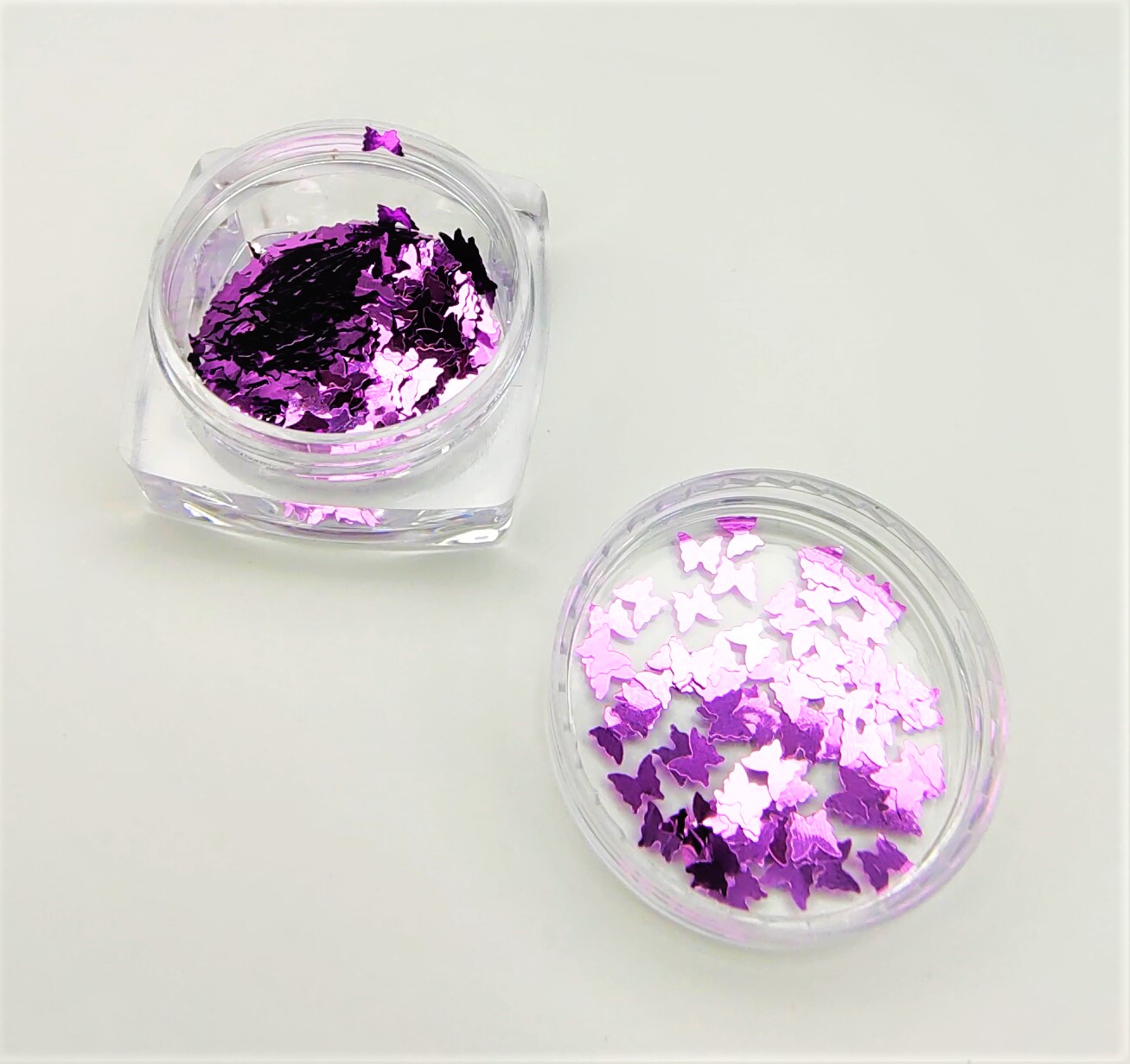 Glitter em forma de borboletas lilás e roxo em caixas transparentes.