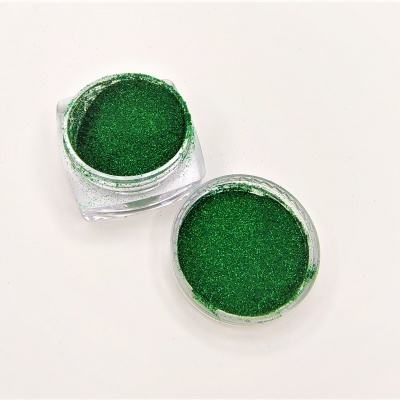 Dois recipientes com glitter verde, um aberto e outro com tampa ao lado, sobre fundo branco.