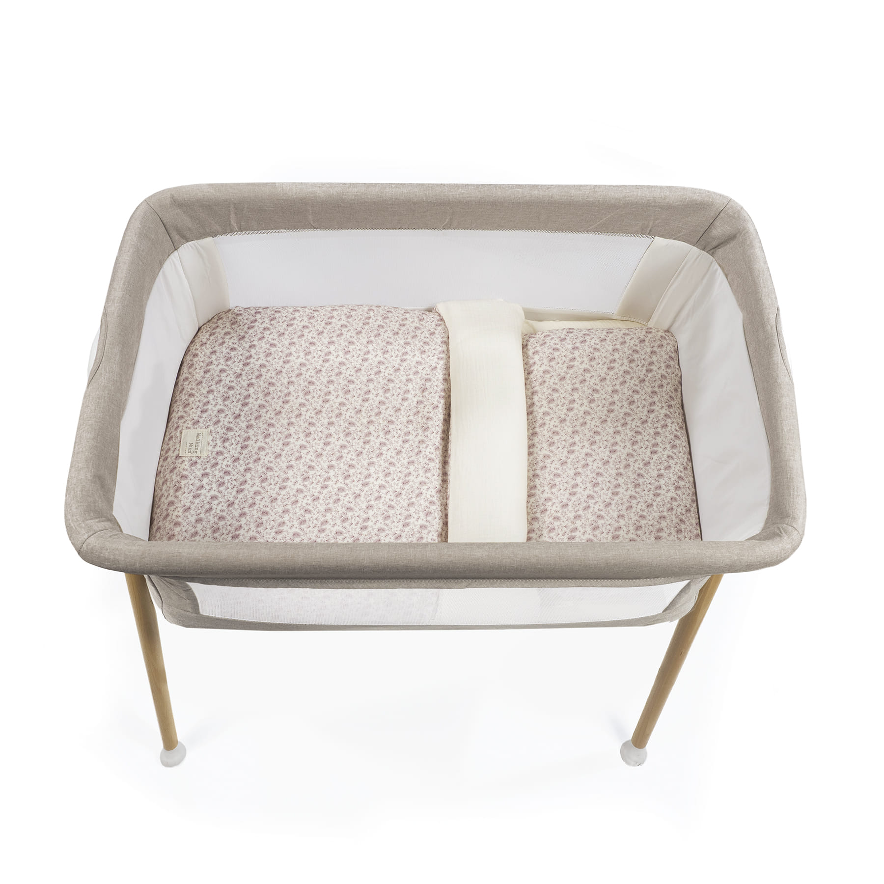 Berço para bebé com colchão estampado e laterais em tecido bege e branco.