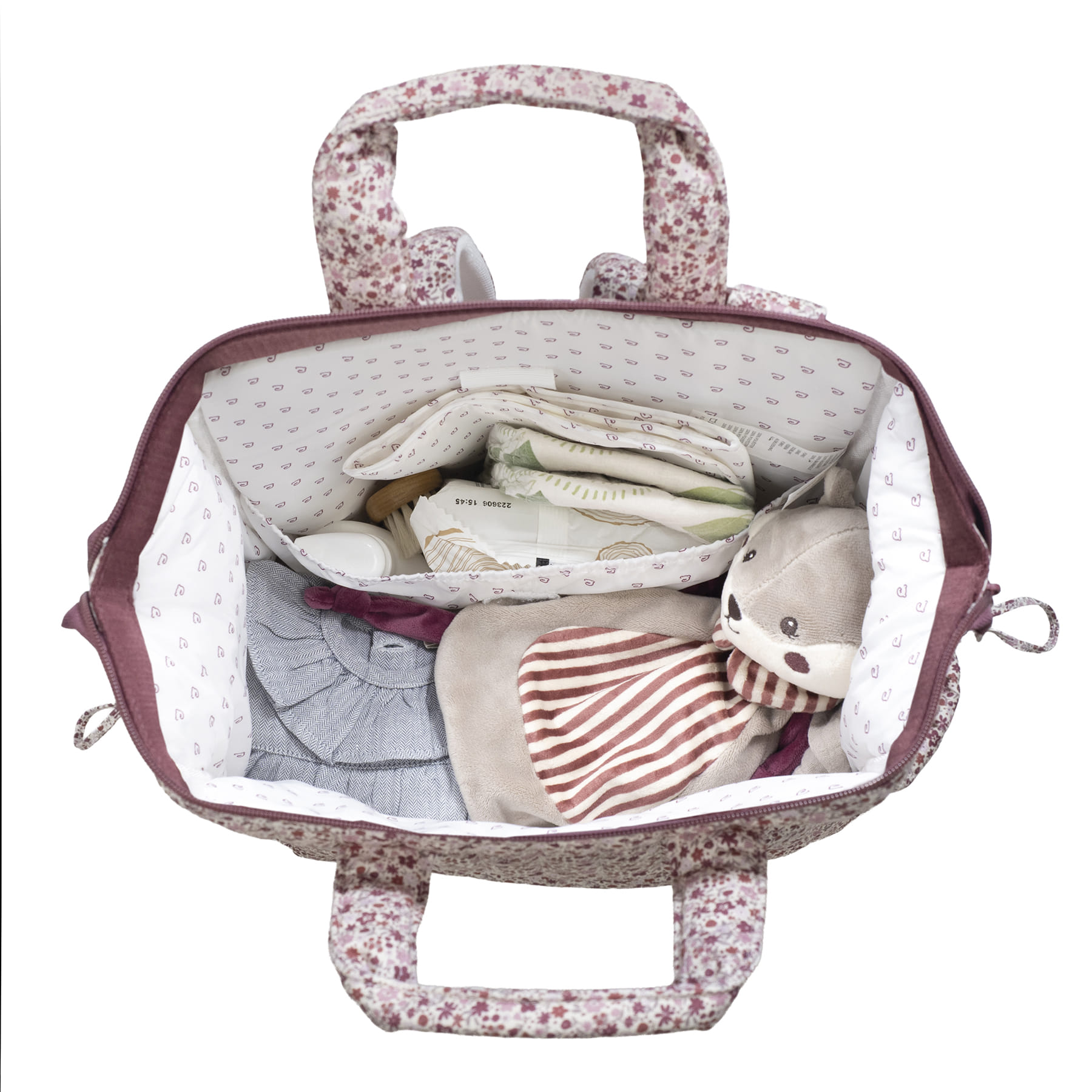 Mala floral rosa e branca para bebé com roupa, fraldas, creme e peluche no interior.