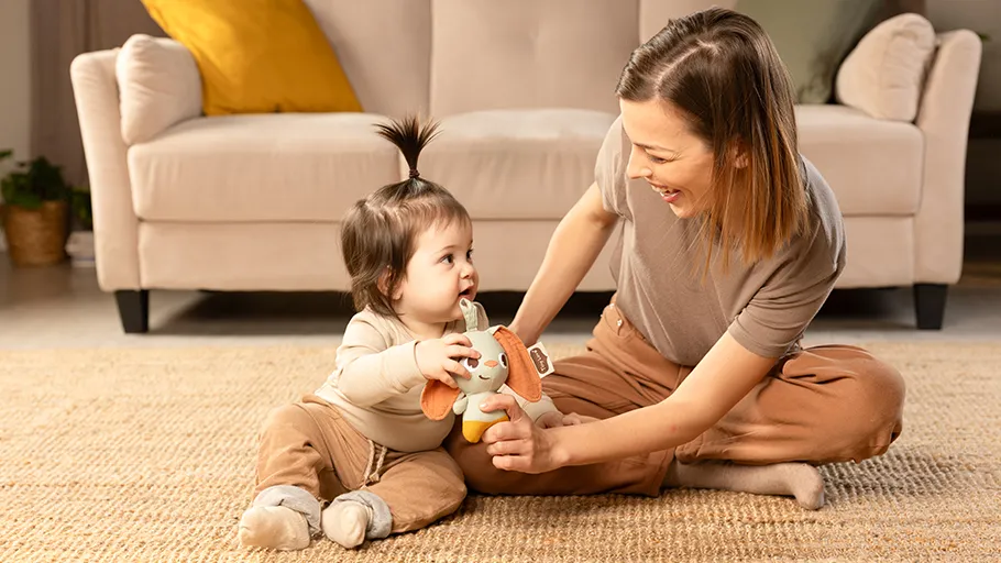 Bebé e mulher sentados no tapete com sofá ao fundo
