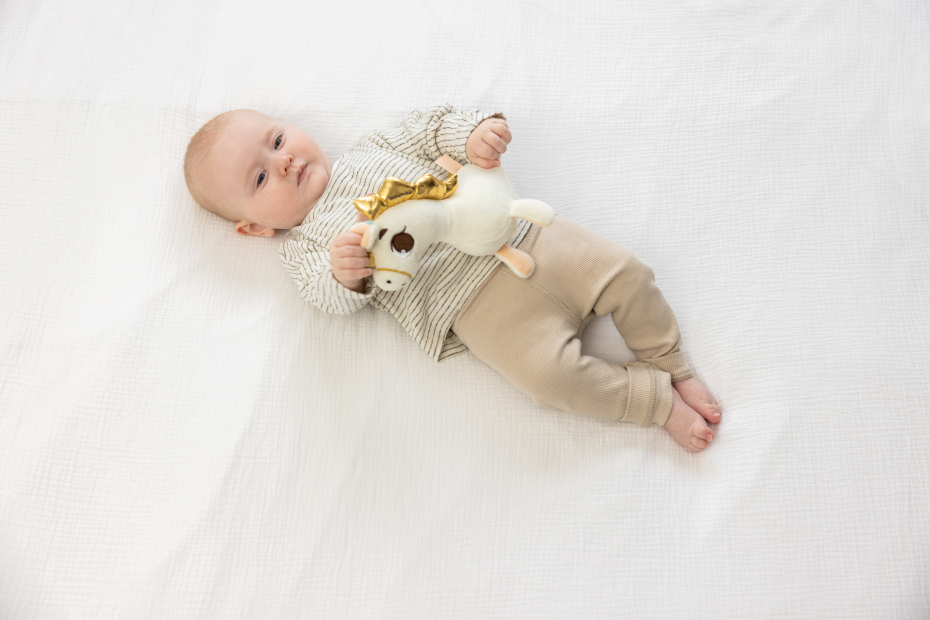 Bebé deitado com roupa bege e peluche branco