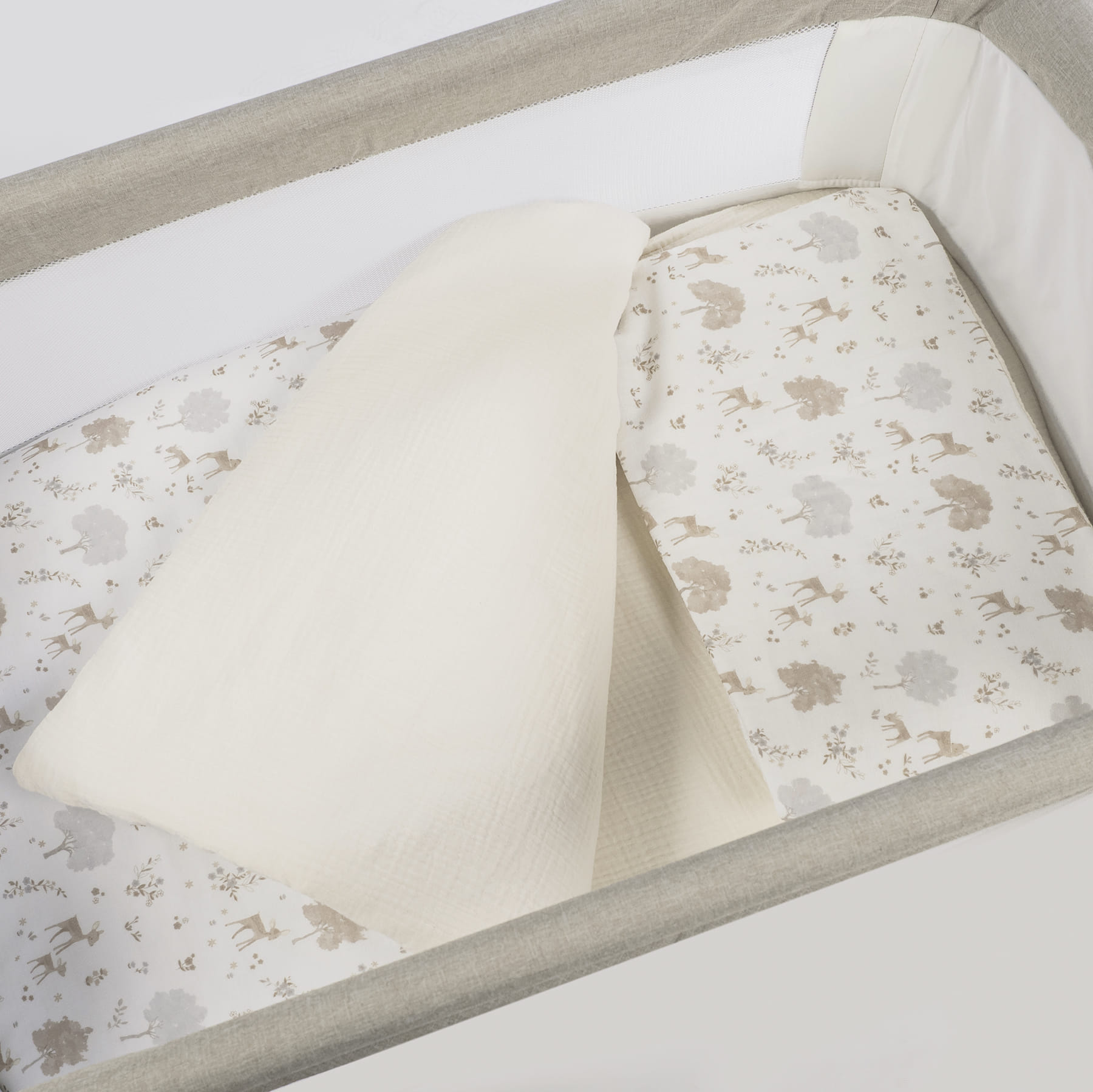 Berço portátil com padrão de veados e árvore no colchão e manta branca