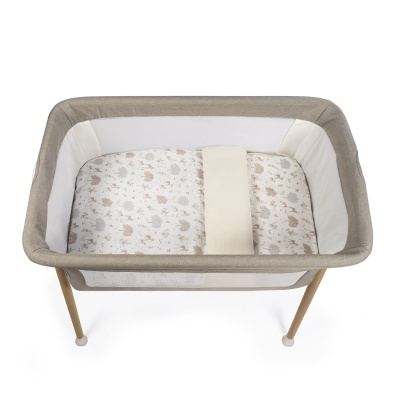 Berço portátil bege com laterais em rede e colchão estampado