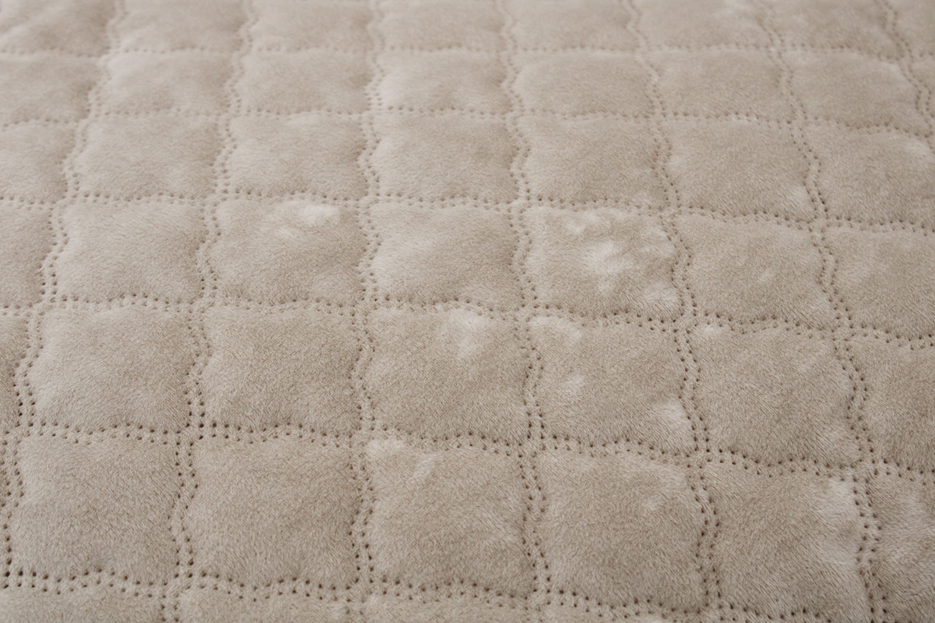 Pano bege com padrão acolchoado em quadrados e linhas perfuradas