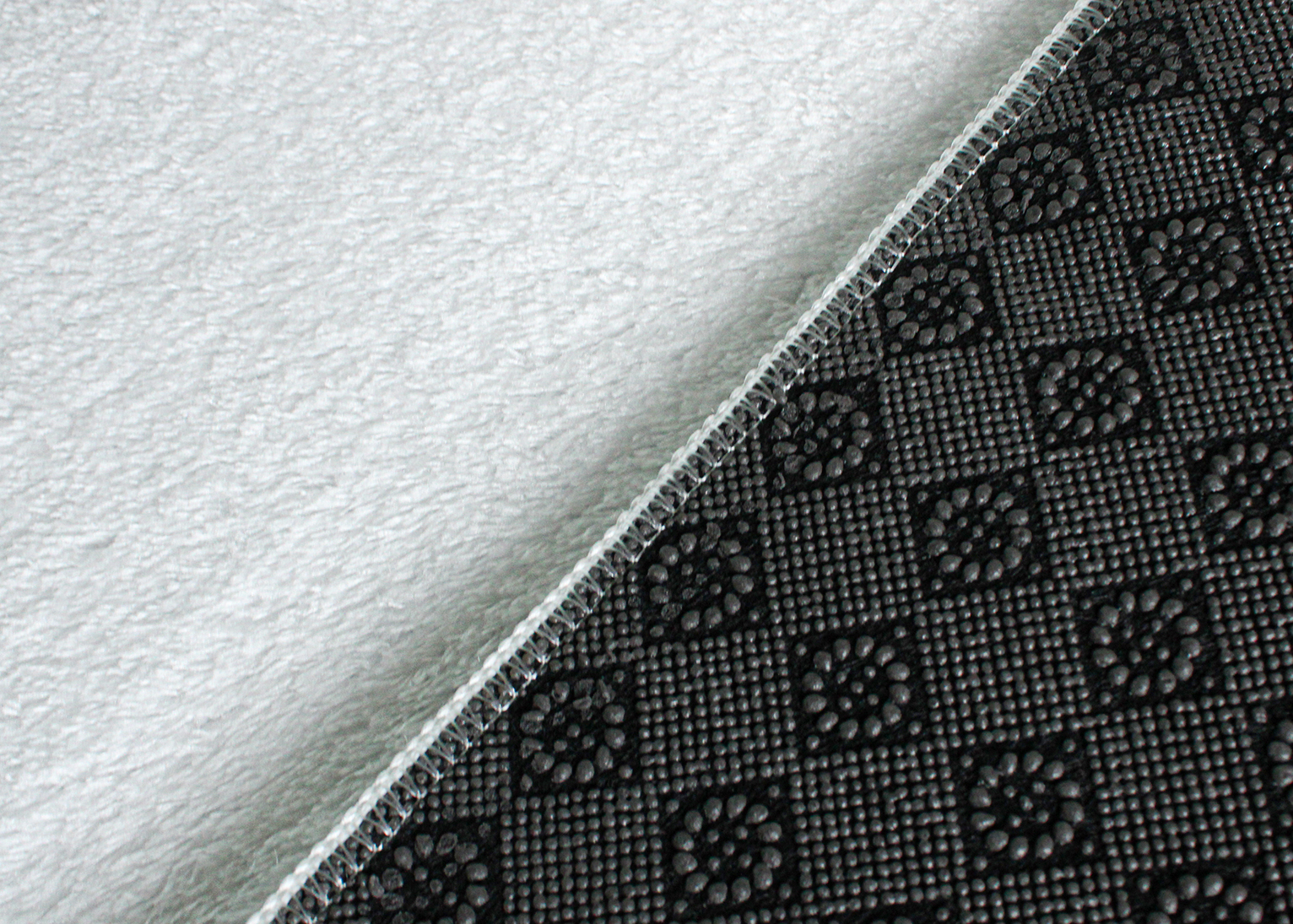 Base antiderrapante preta com padrão em relevo e superfície branca felpuda