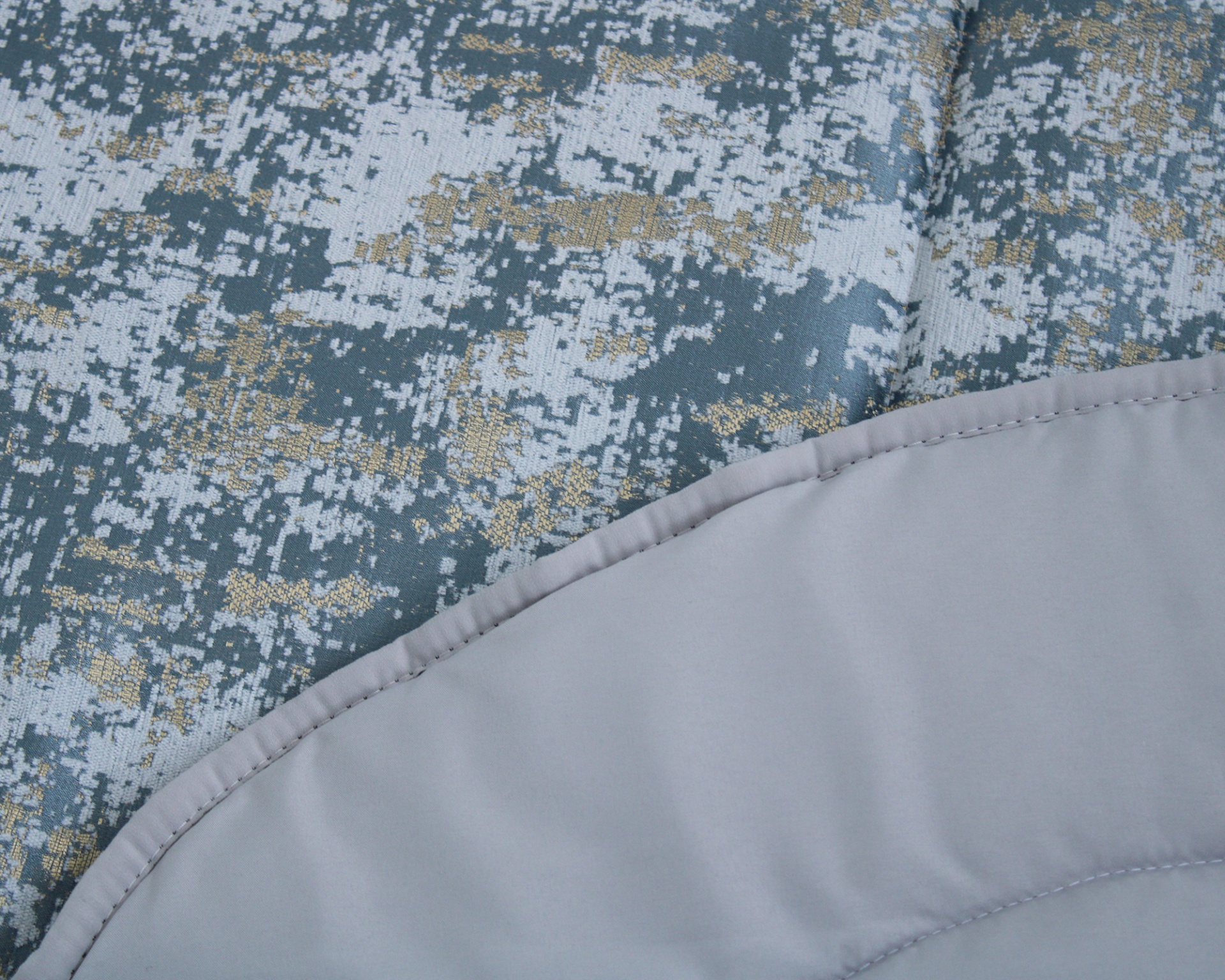 Tecido com padrão digital azul, branco e dourado, e tecido cinzento com costura.