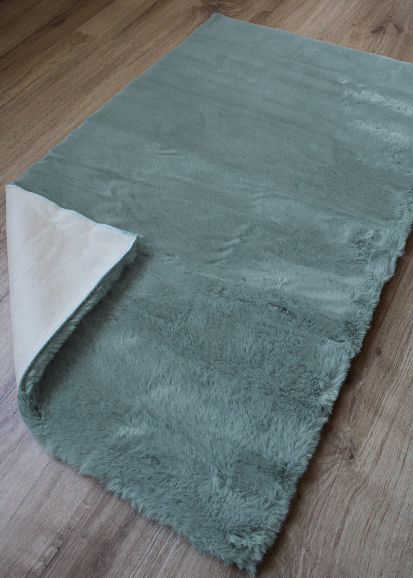Tapete azul esverdeado felpudo sobre chão de madeira
