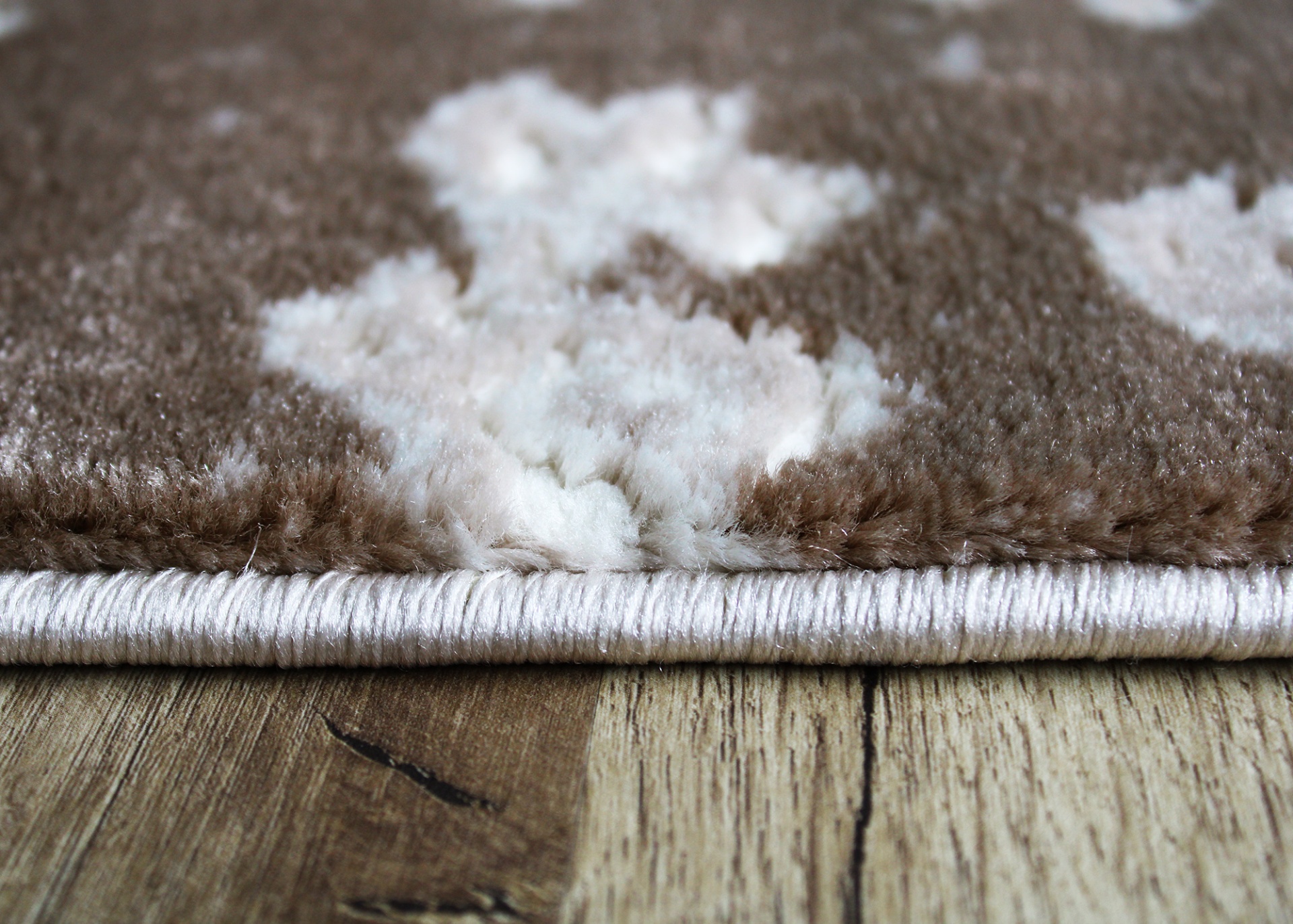 Tapete castanho e branco sobre chão de madeira clara