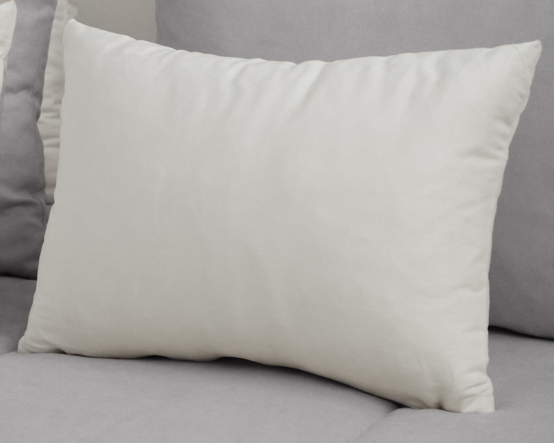Travesseiro branco retangular sobre superfície cinza