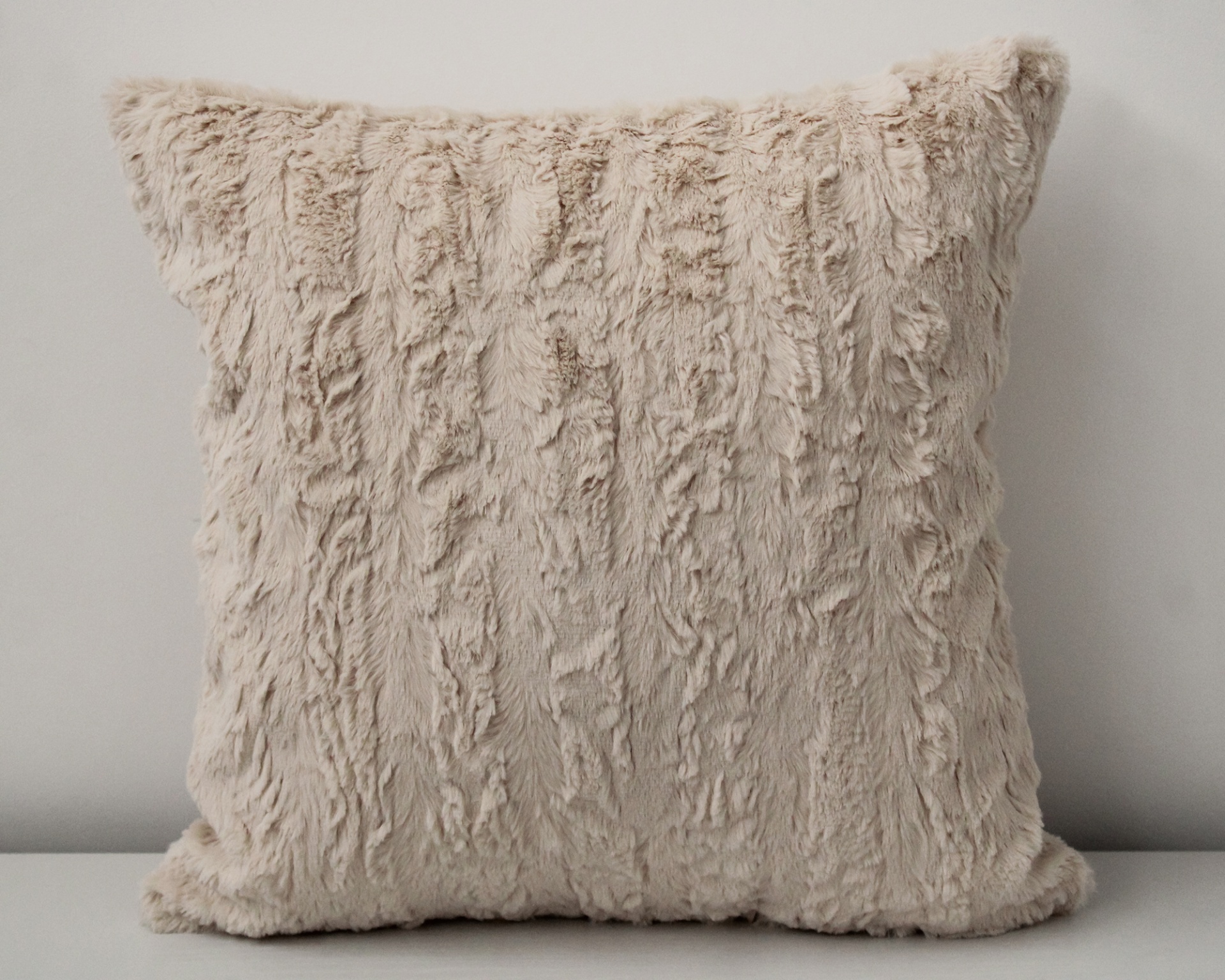 Almofada felpuda bege claro em fundo branco