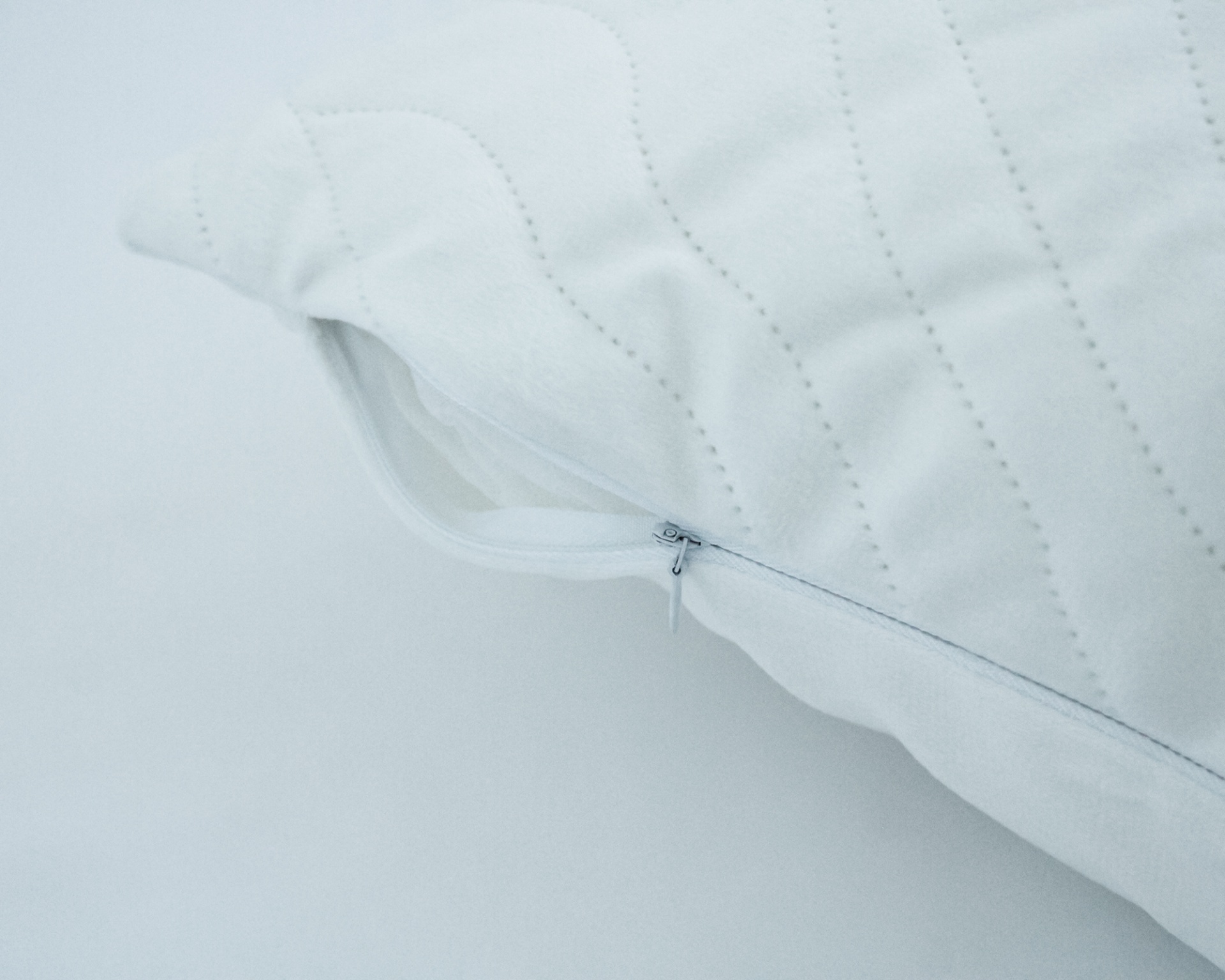 Almofada branca matelassada com zíper aberto