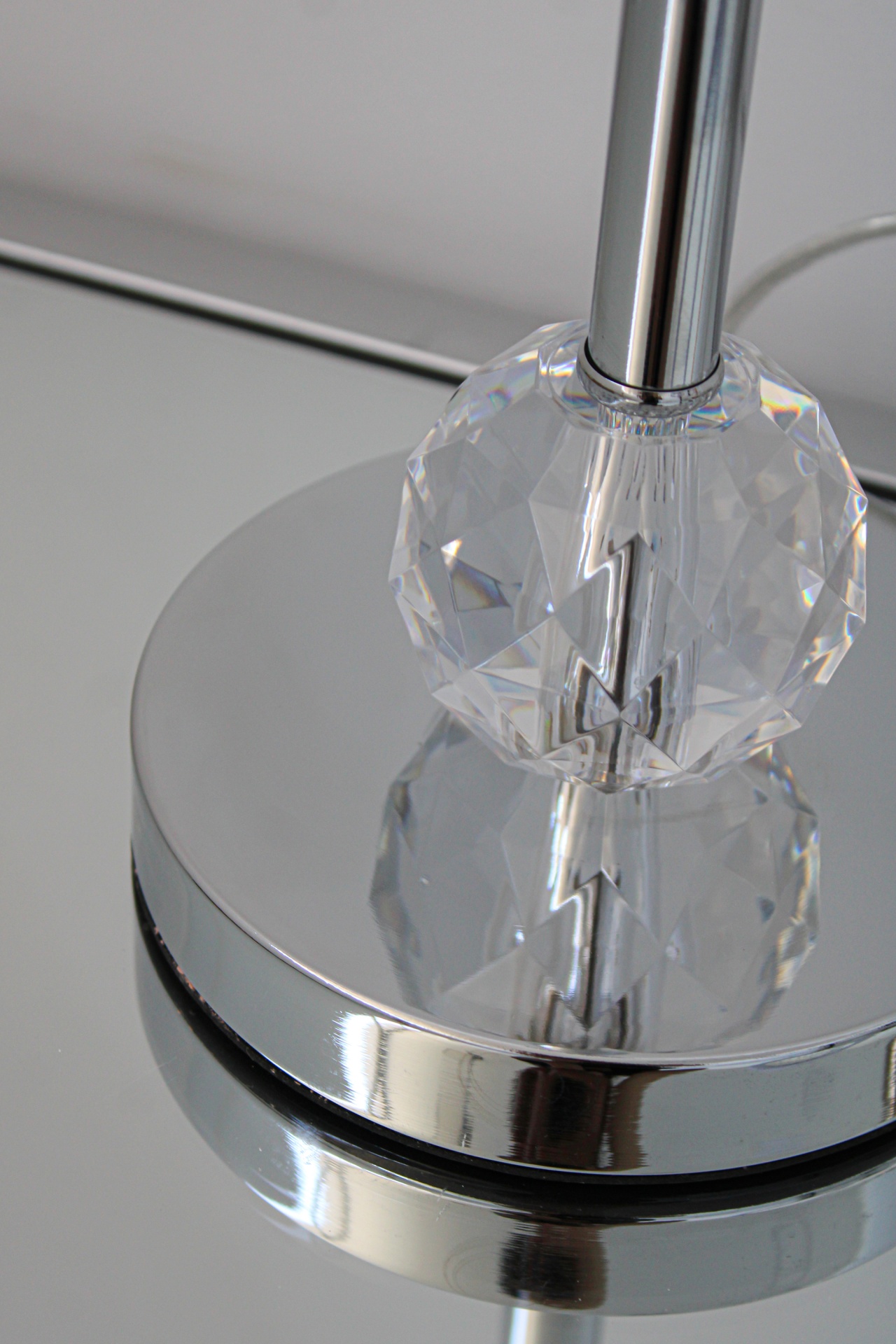 Base metálica espelhada com objeto facetado transparente e suporte cilíndrico prateado