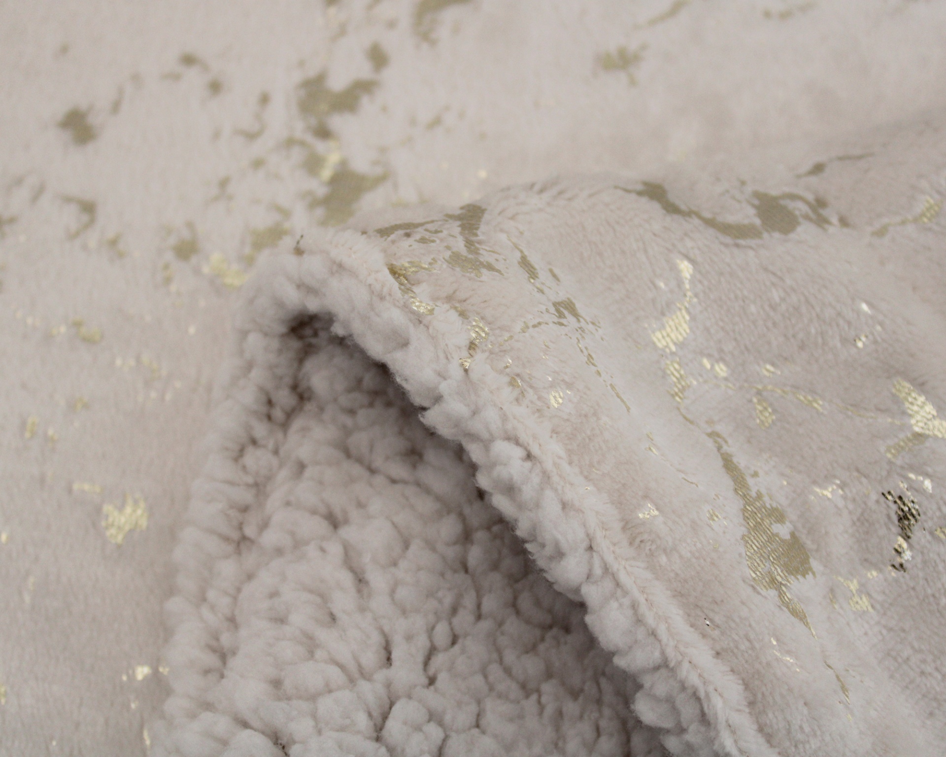 Manta cinzento claro com padrão dourado e textura felpuda