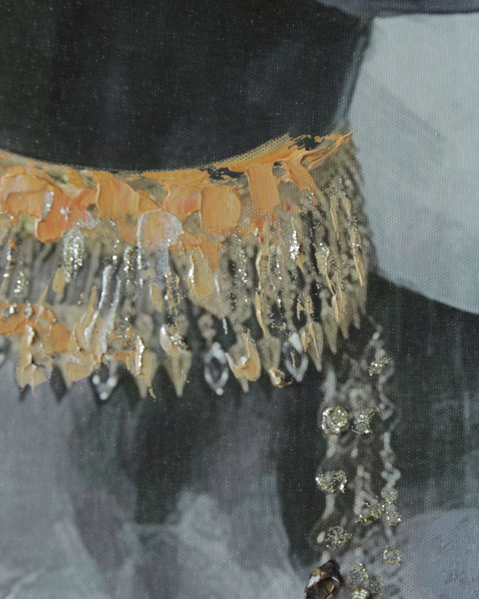 Pormenor de colar dourado com franjas pendentes e brilho sobre fundo escuro e cinzento.