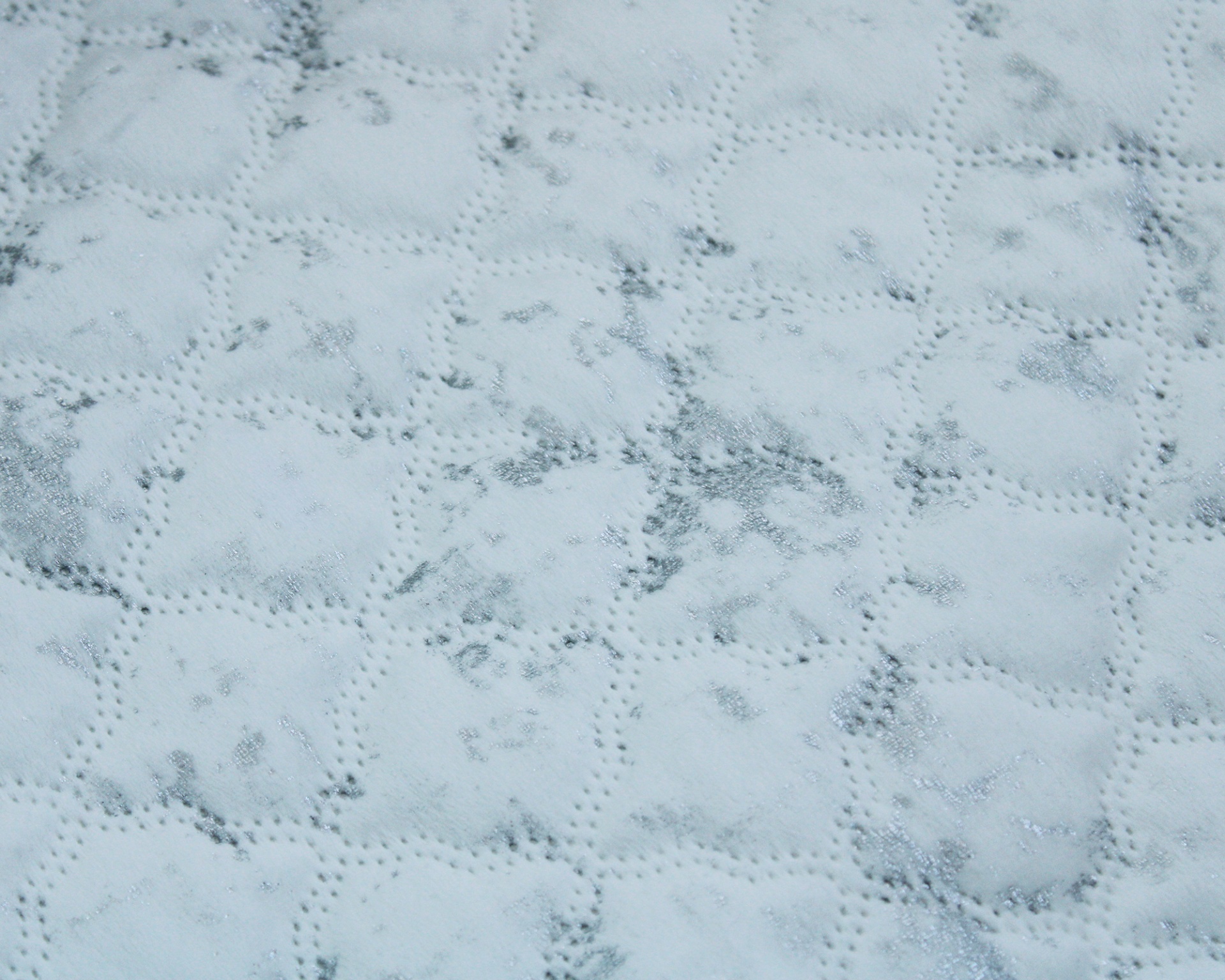 Tecido acolchoado branco com padrão de manchas cinzentas e costura em quadrados