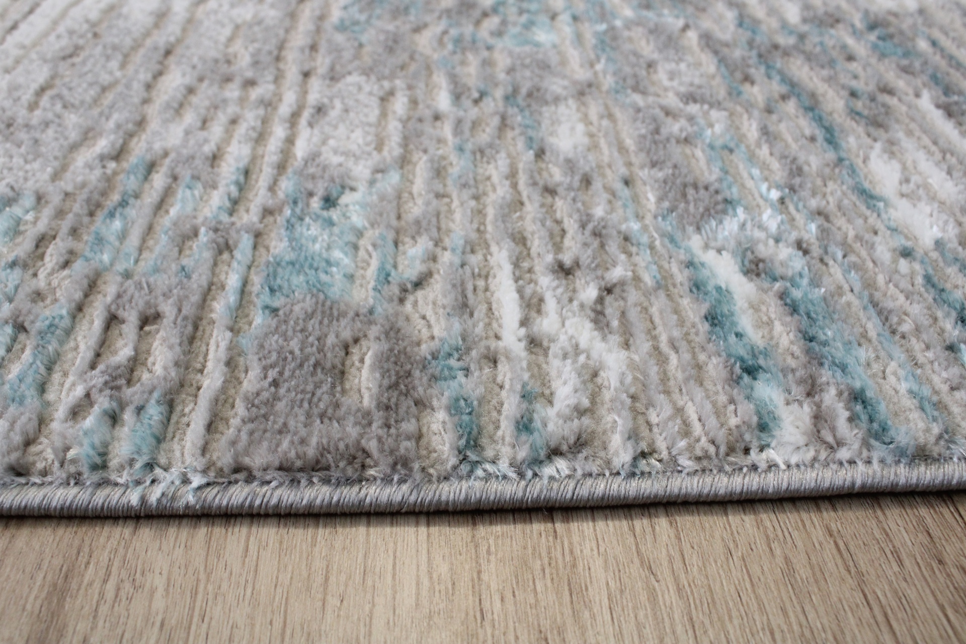 Tapete cinza, branco e azul claro sobre chão de madeira clara