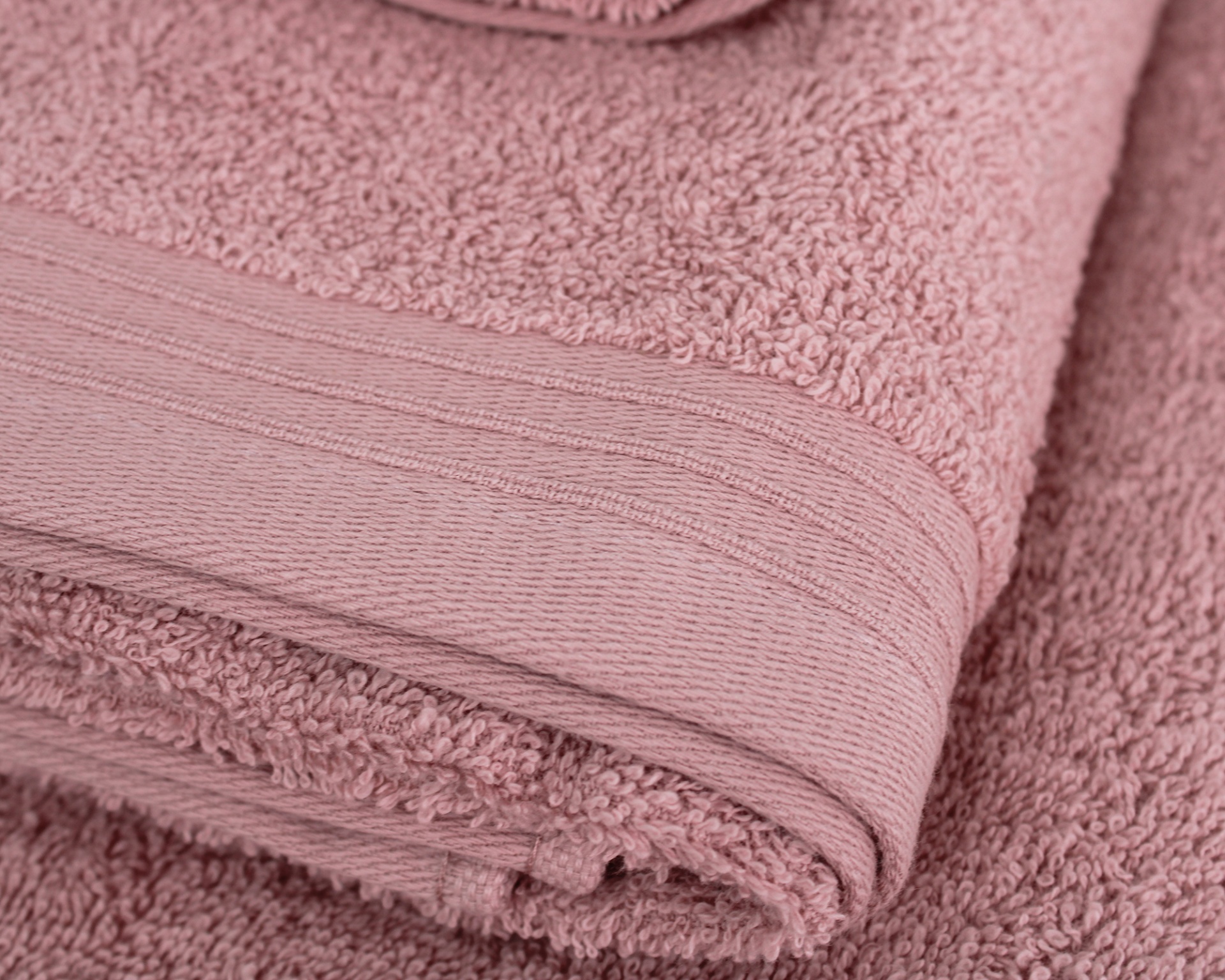 Toalha de banho rosa dobrada com faixa texturada