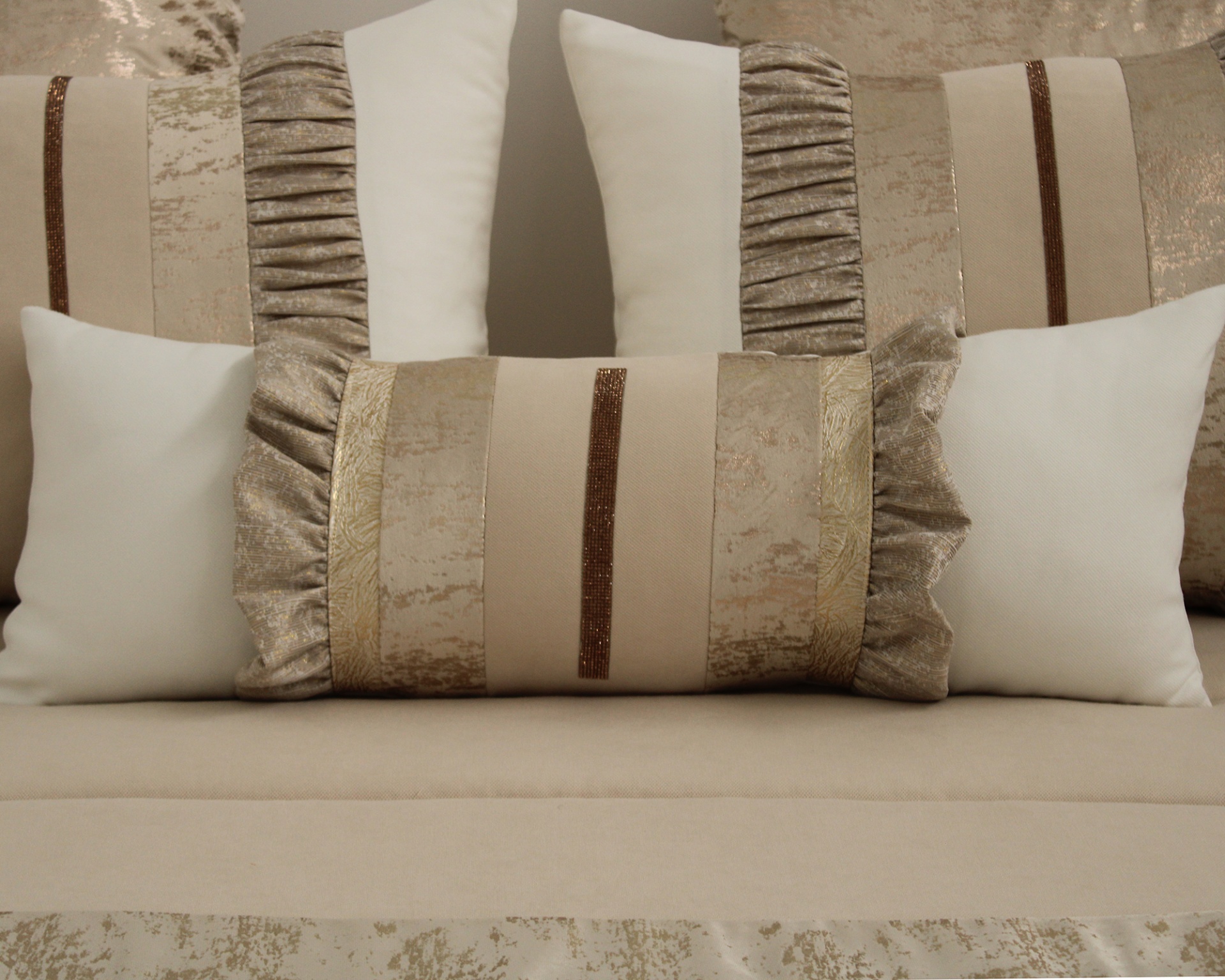 Almofadas decorativas bege e douradas num sofá bege