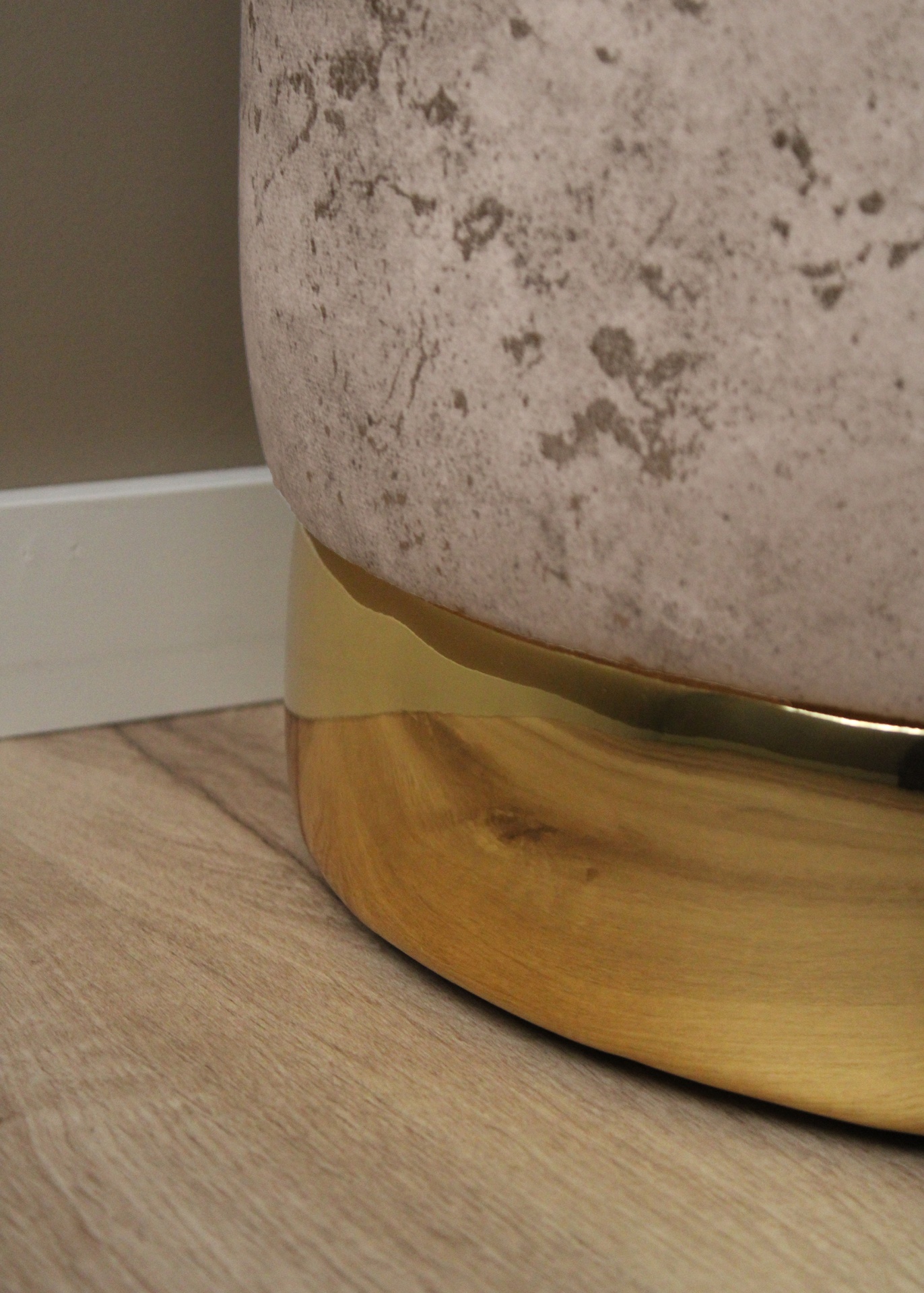 Móvel com tecido cinza claro e base metálica dourada sobre pavimento de madeira