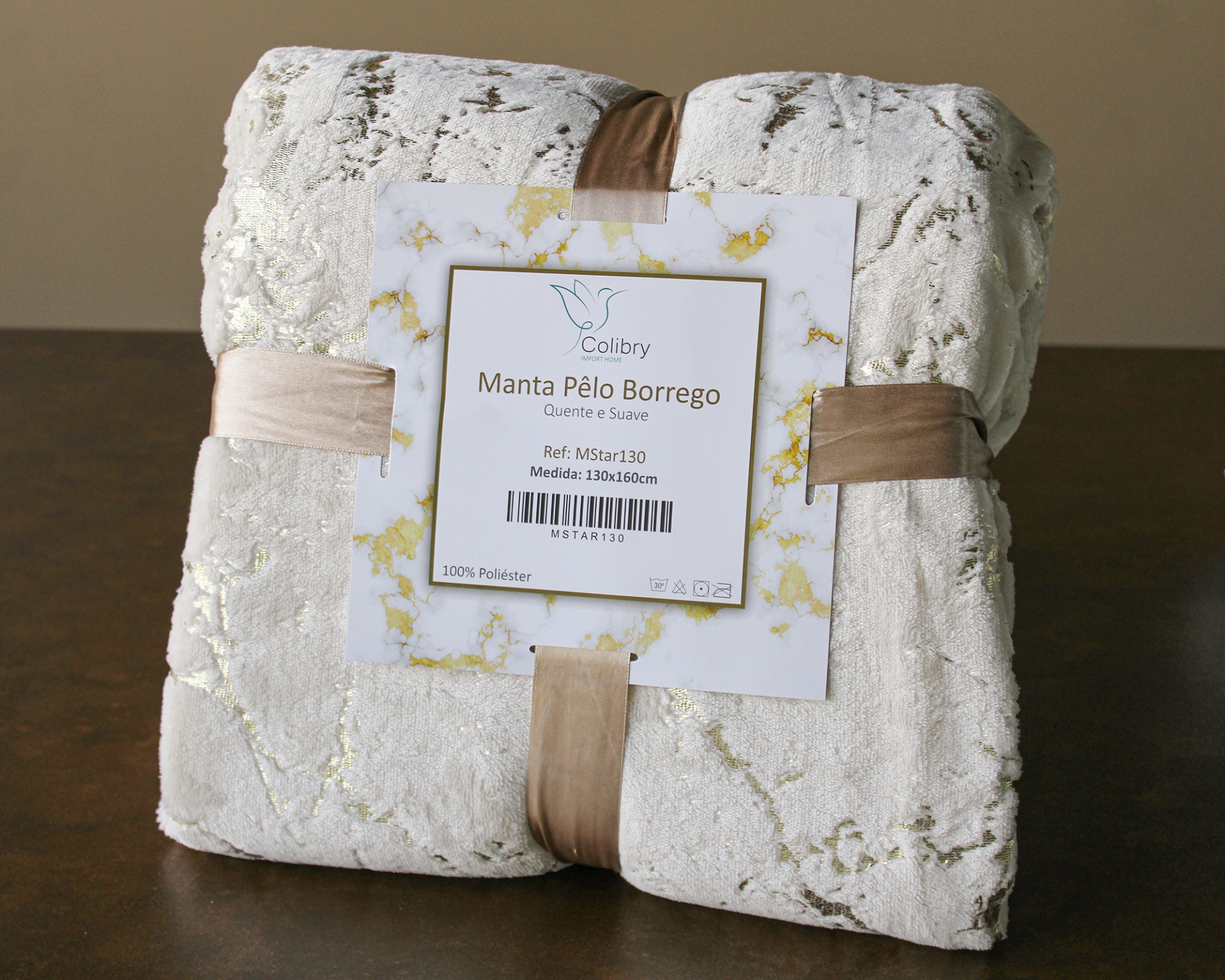 manta branca com padrão dourado e etiqueta com informações da marca e tamanho