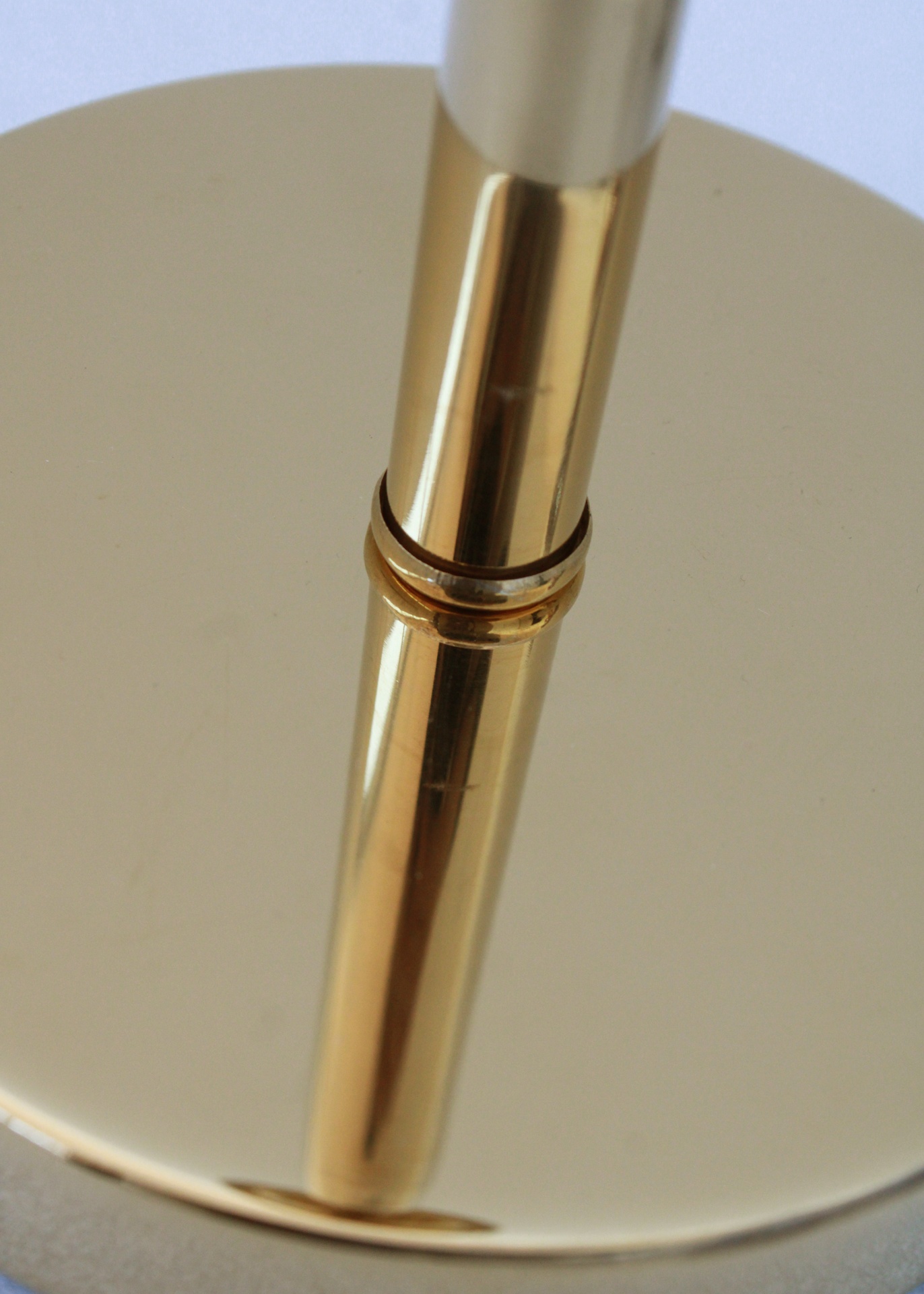 Base circular dourada com tubo refletido na superfície