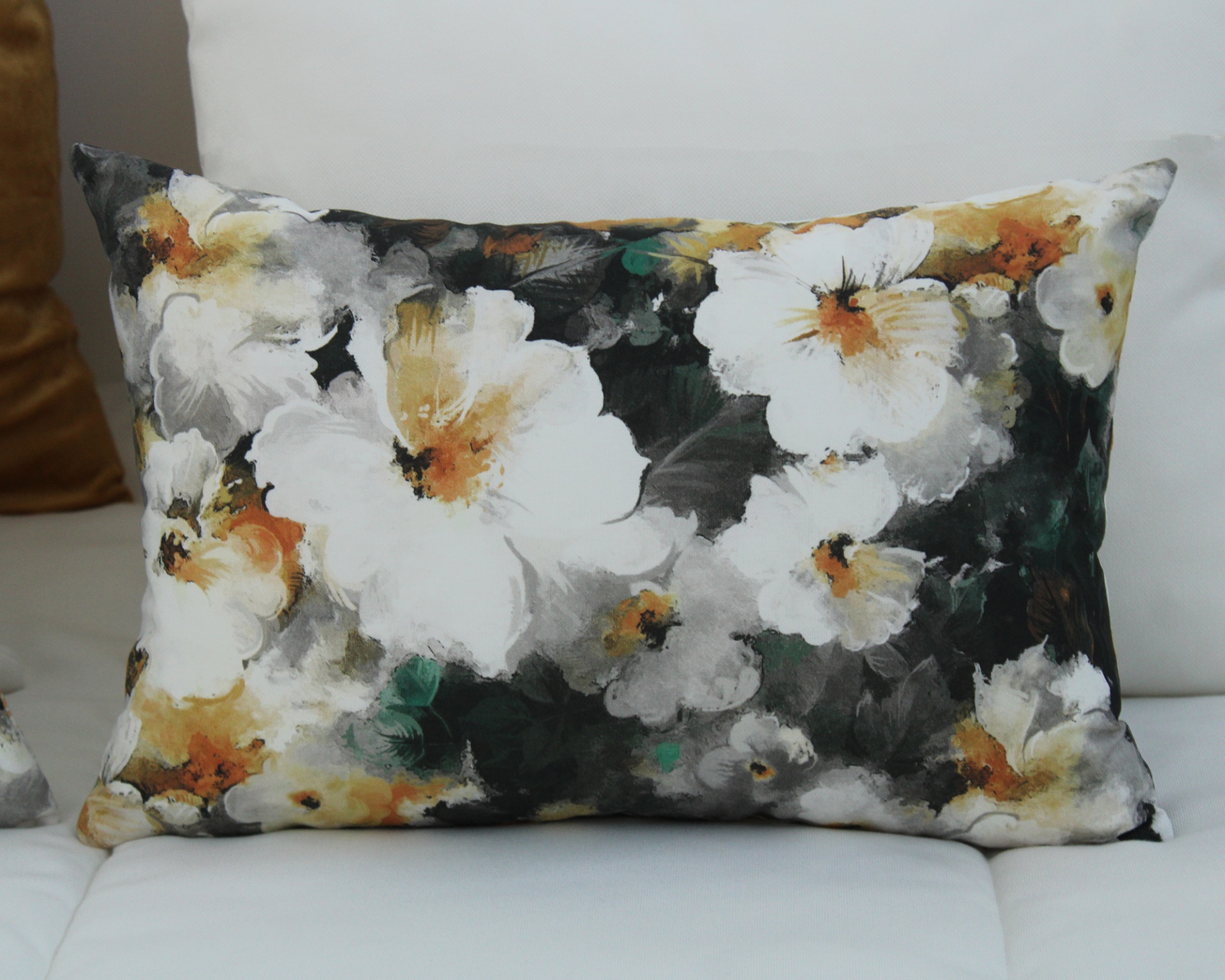 Almofada decorativa retangular com flores brancas e amarelas sobre fundo escuro