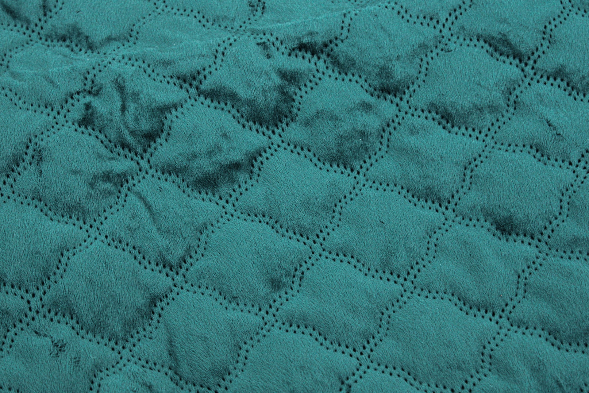 Tecido têxtil azul turquesa com padrão em relevo de losangos e pequenos furos decorativos