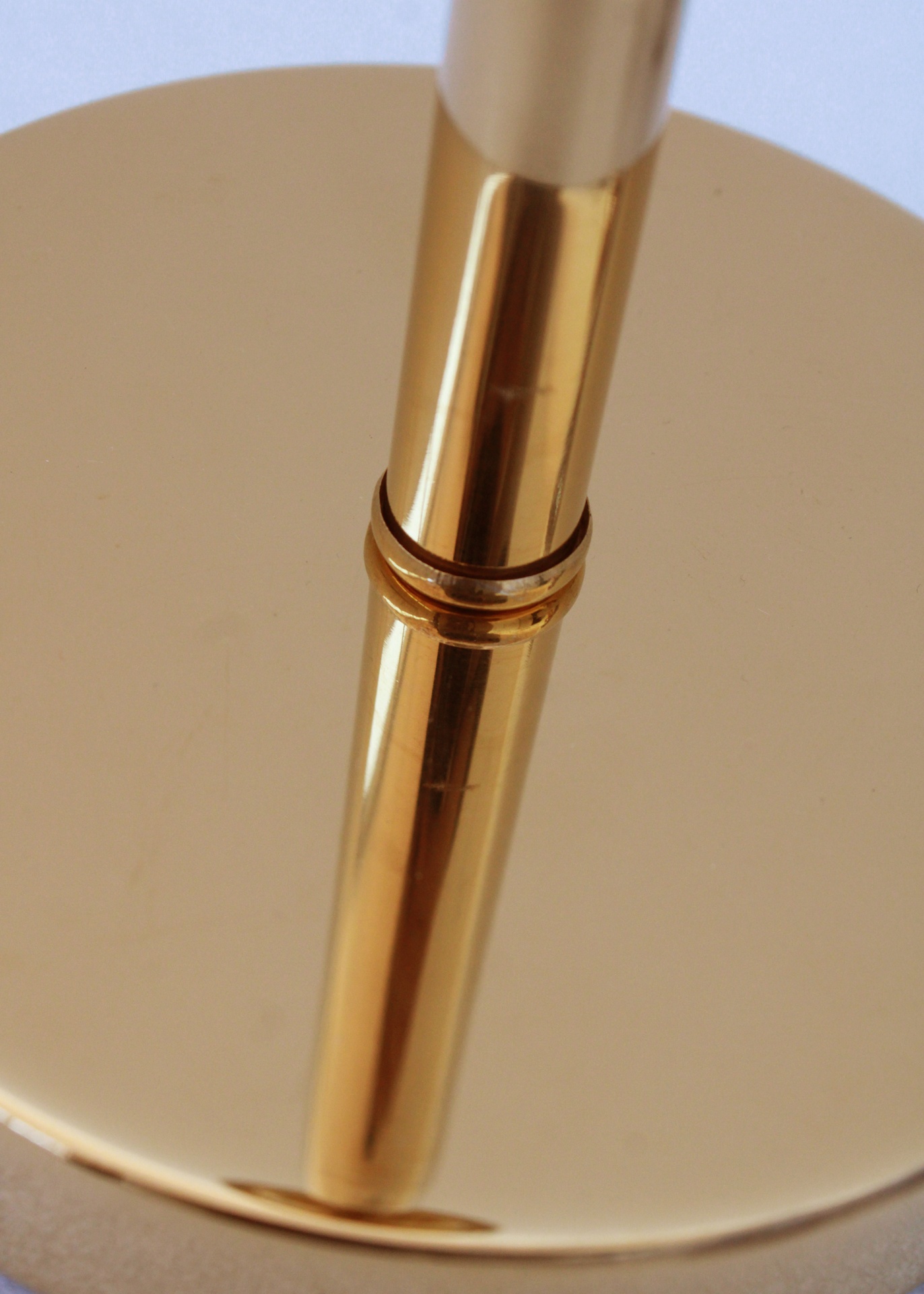 Estrutura metálica dourada com acabamento brilhante e disco circular