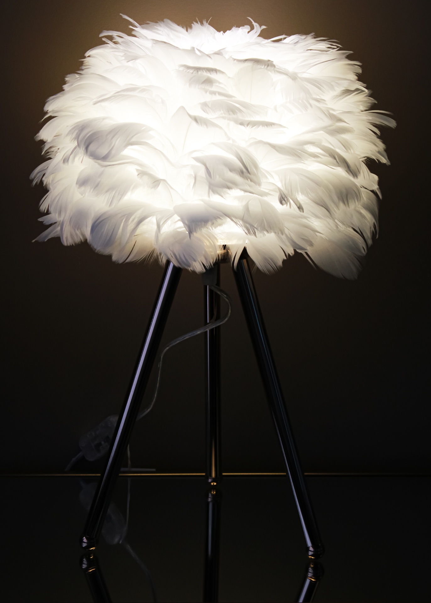 Candeeiro de mesa com abajur de penas brancas e base tripé preta