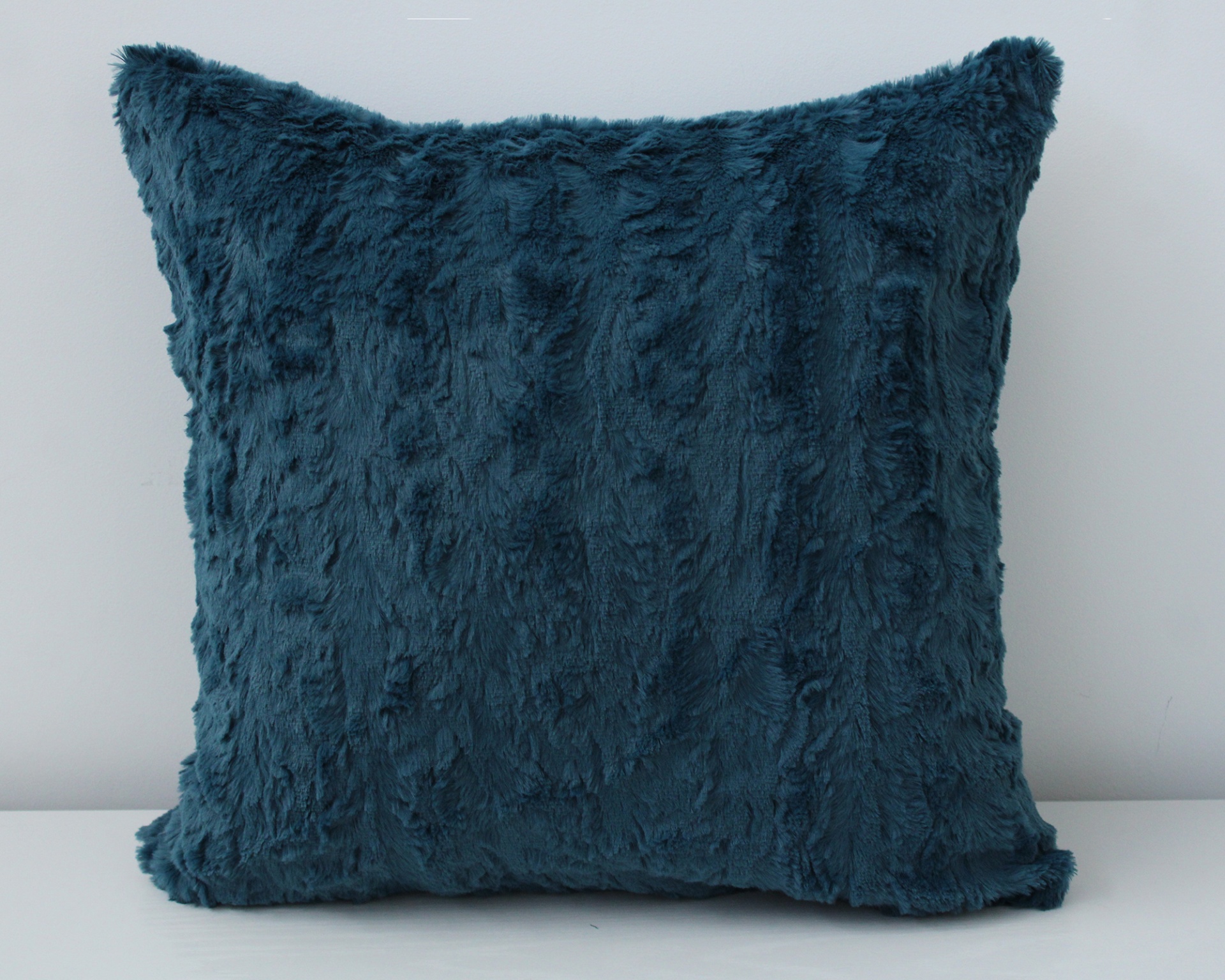 Almofada azul escura felpuda sobre superfície branca