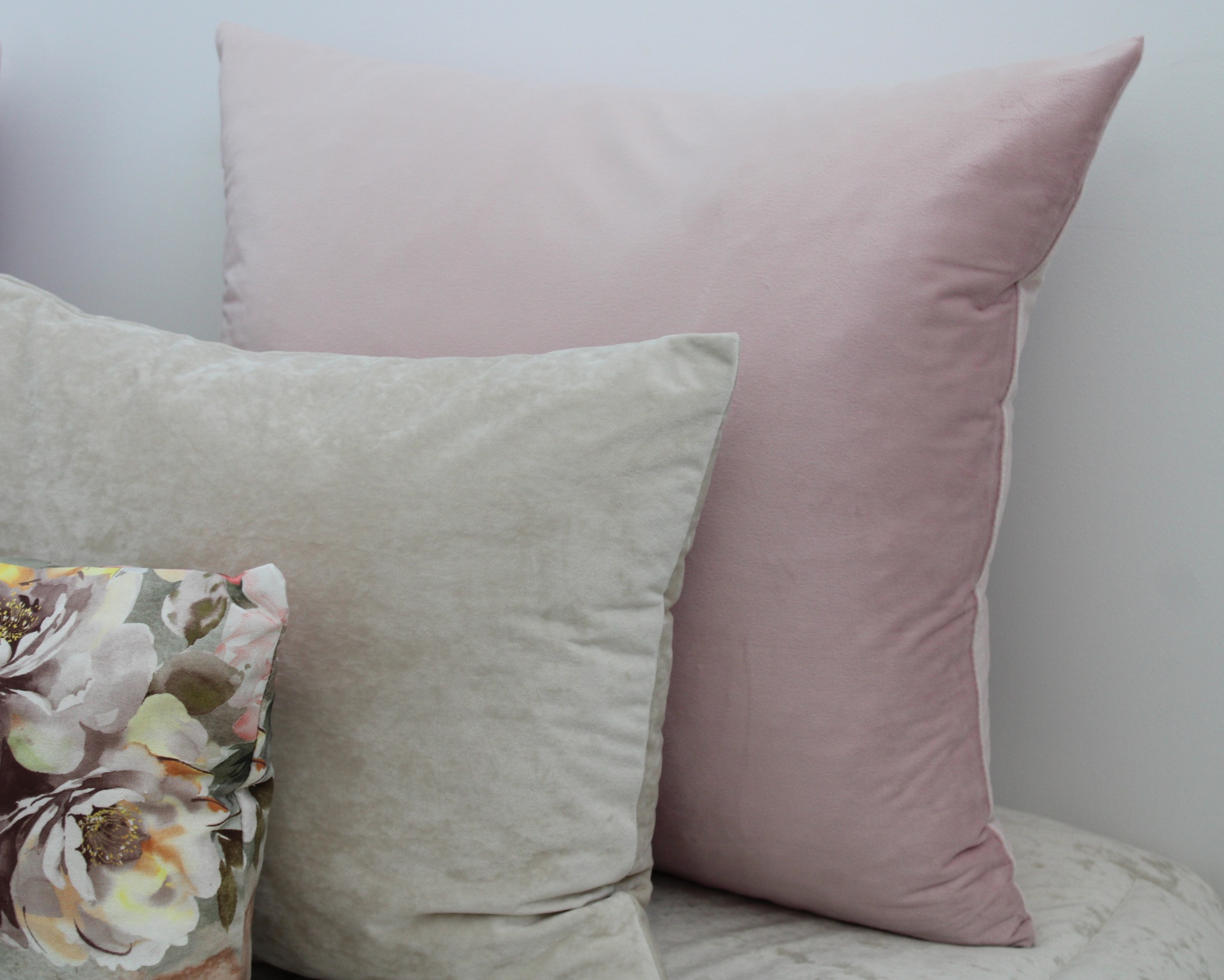 Conjunto de almofadas em rosa, cinza e floral sobre superfície clara