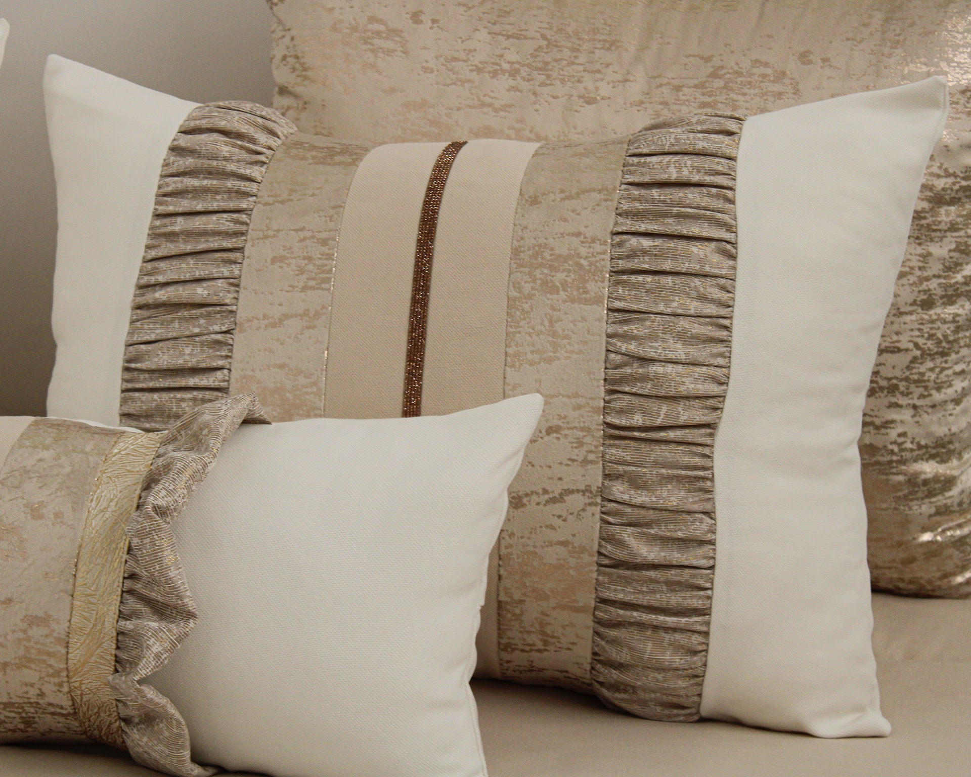 Almofadas decorativas bege, branco e dourado com texturas variadas
