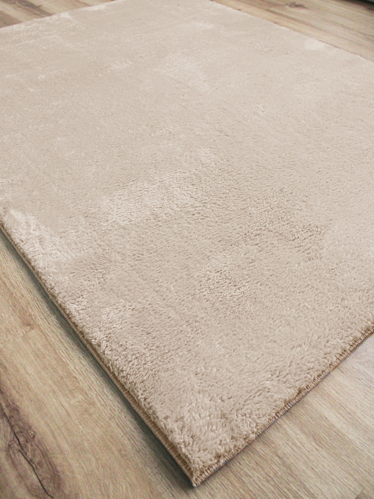 Tapete bege claro com textura macia sobre chão de madeira clara