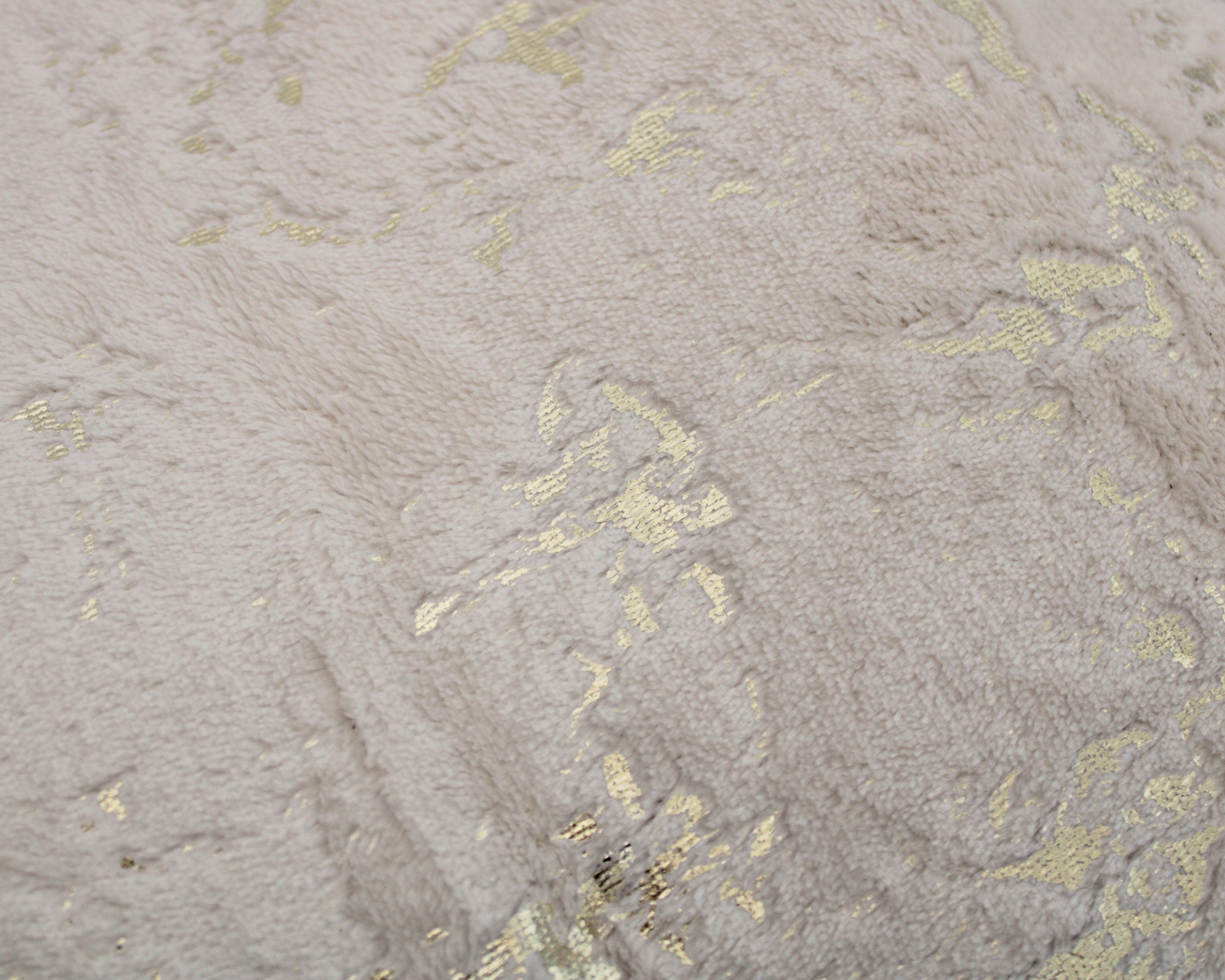 Tecido felpudo creme com detalhes dourados.