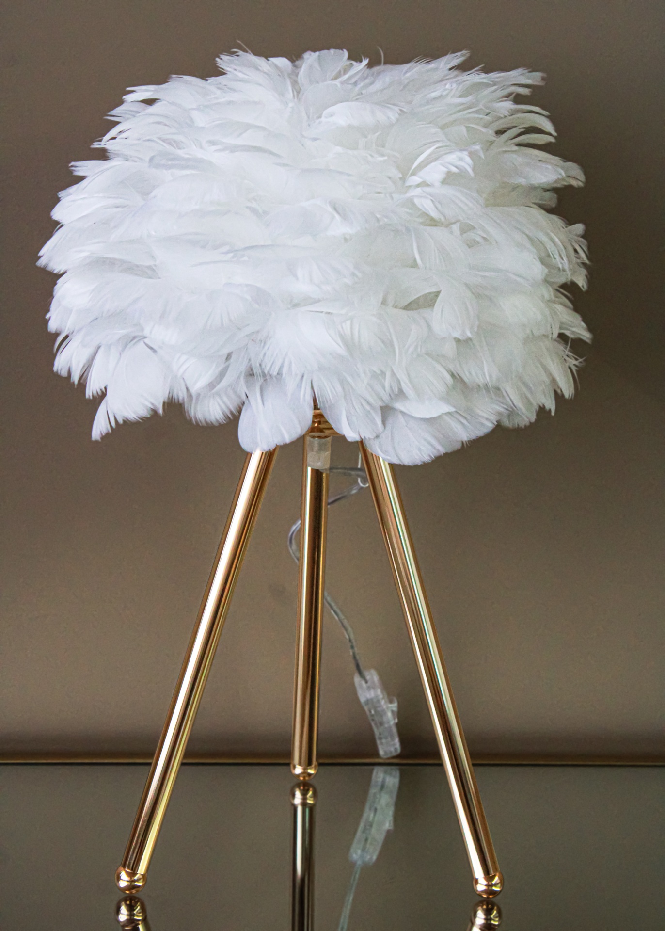 Candeeiro de mesa com cúpula de penas brancas e base dourada tripé