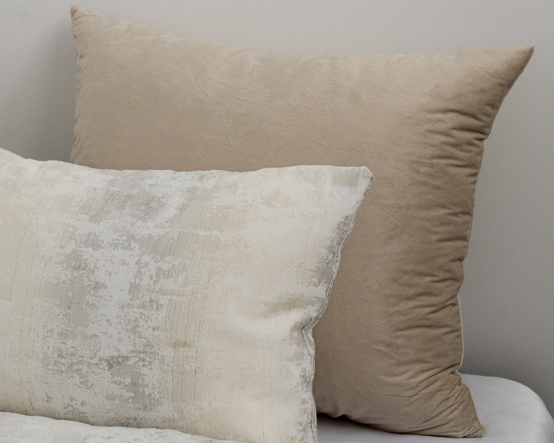 Dois almofadas, uma bege lisa e outra com padrão branco e cinza