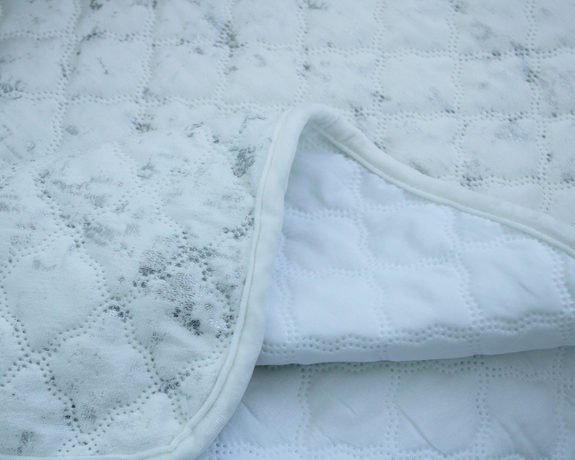 Colchão ou capa acolchoada branca com manchas escuras visíveis