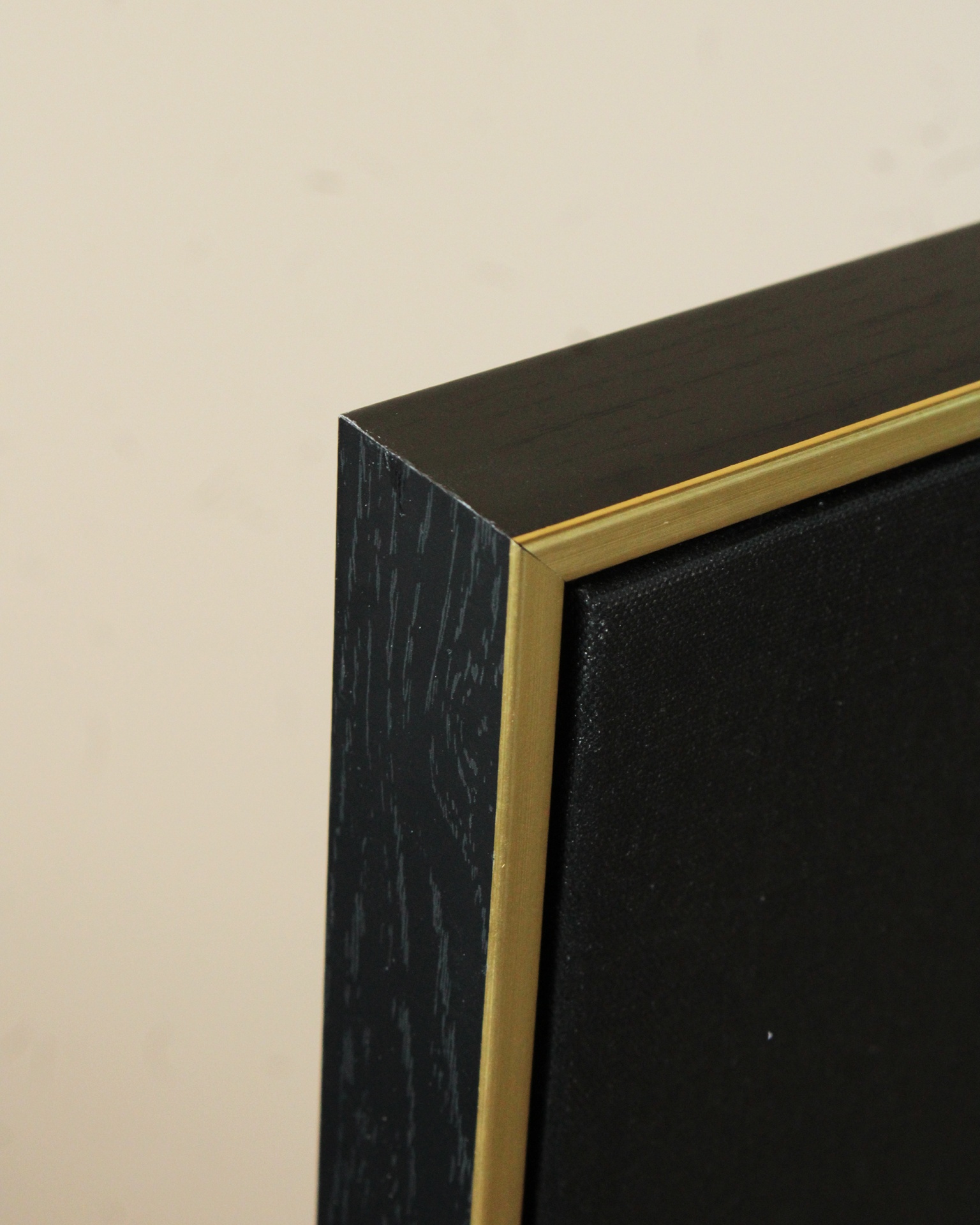 Moldura preta em madeira com borda dourada e painel preto