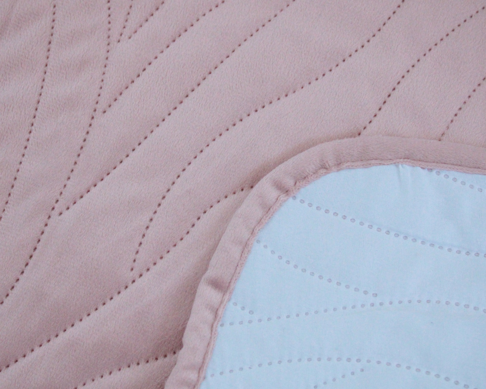 tecido acolchoado rosa claro com detalhes em branco e costura ondulada