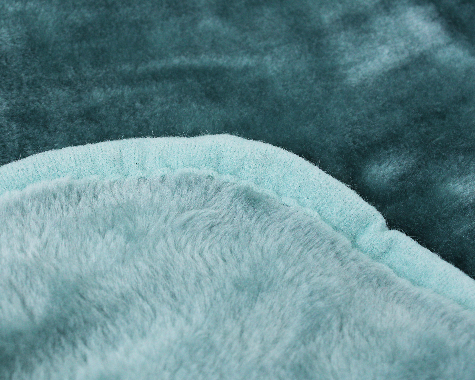 Toalha ou roupão azul claro em tecido felpudo sobre superfície azul escura