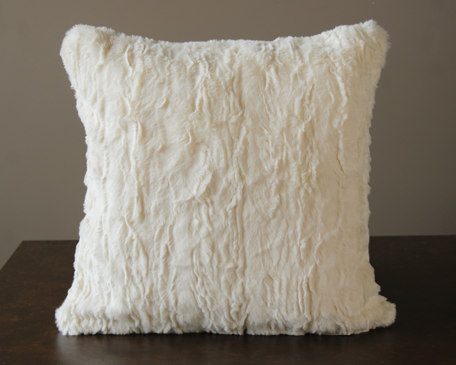 Almofada branca felpuda com padrão irregular colocada sobre superfície escura