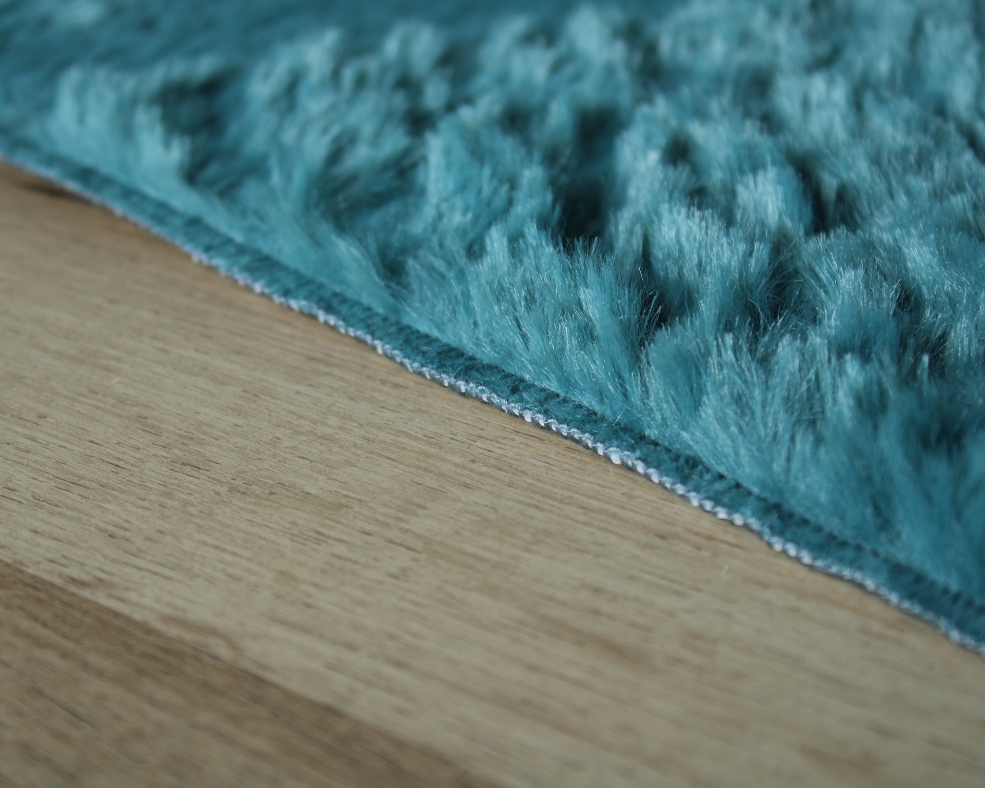 Tapete peludo azul turquesa sobre chão de madeira clara