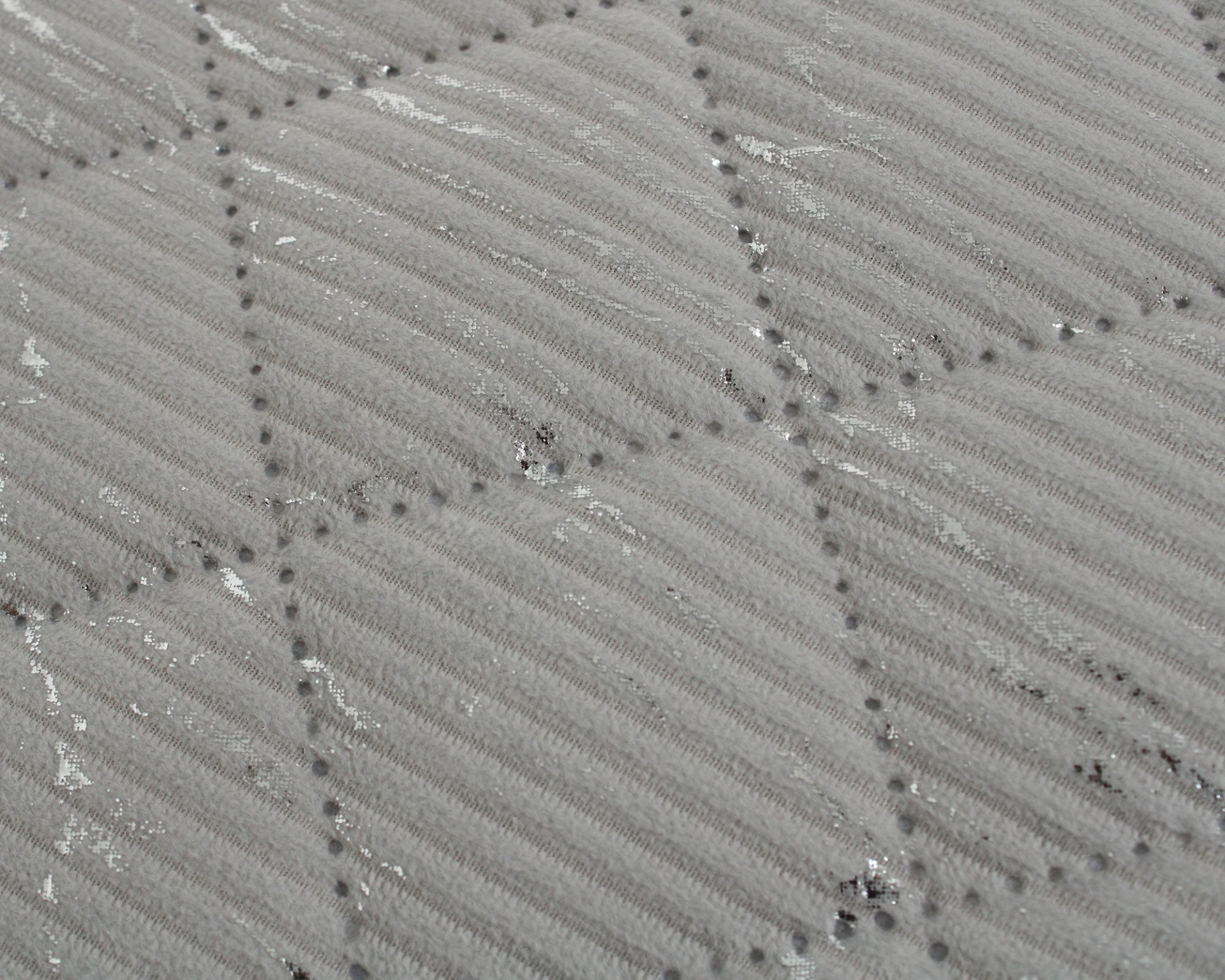 padrão texturizado em tecido cinzento claro com linhas onduladas e costuras formando quadrados