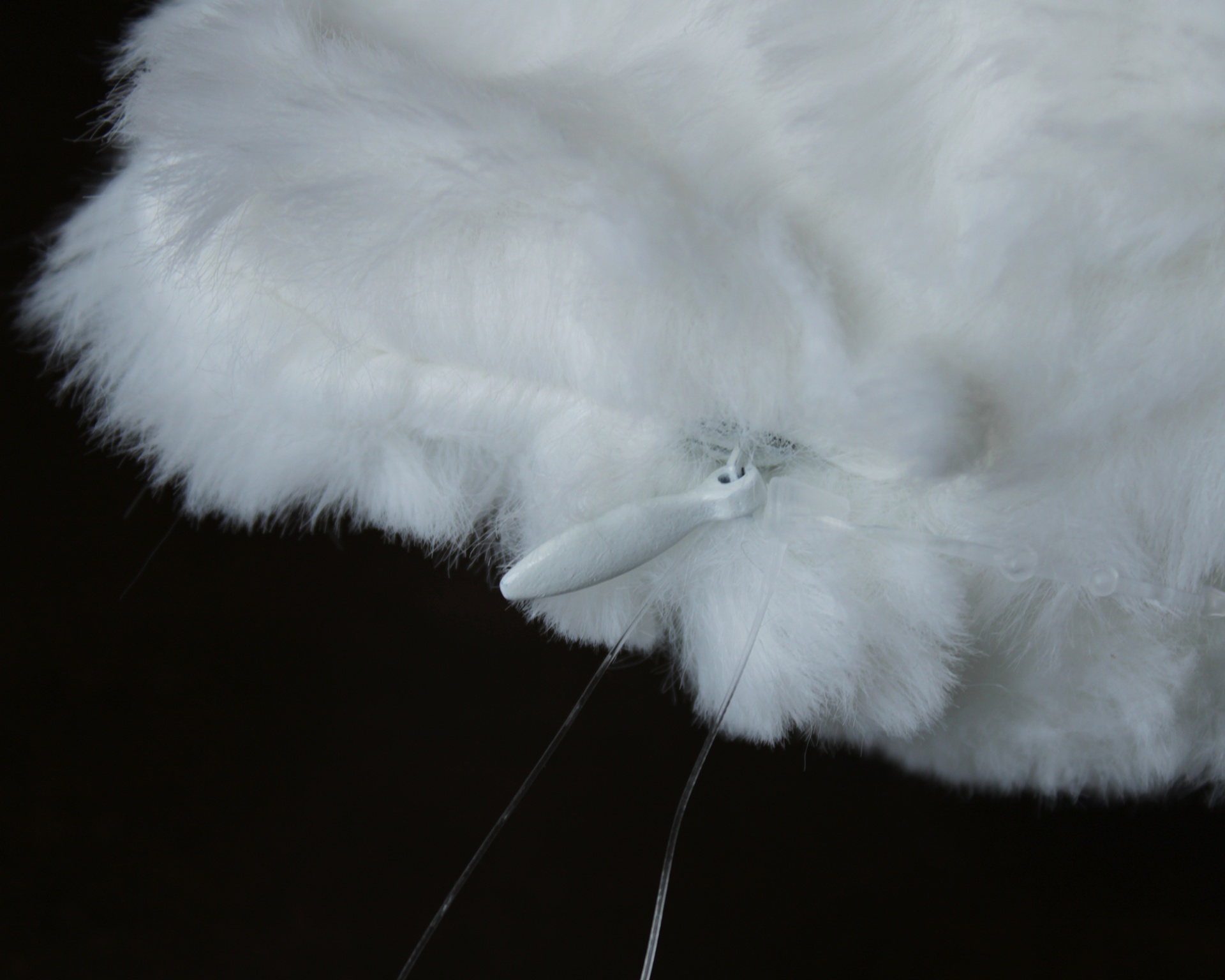 Pano de limpeza branco peludo com ponteira branca e fios transparentes sobre fundo preto