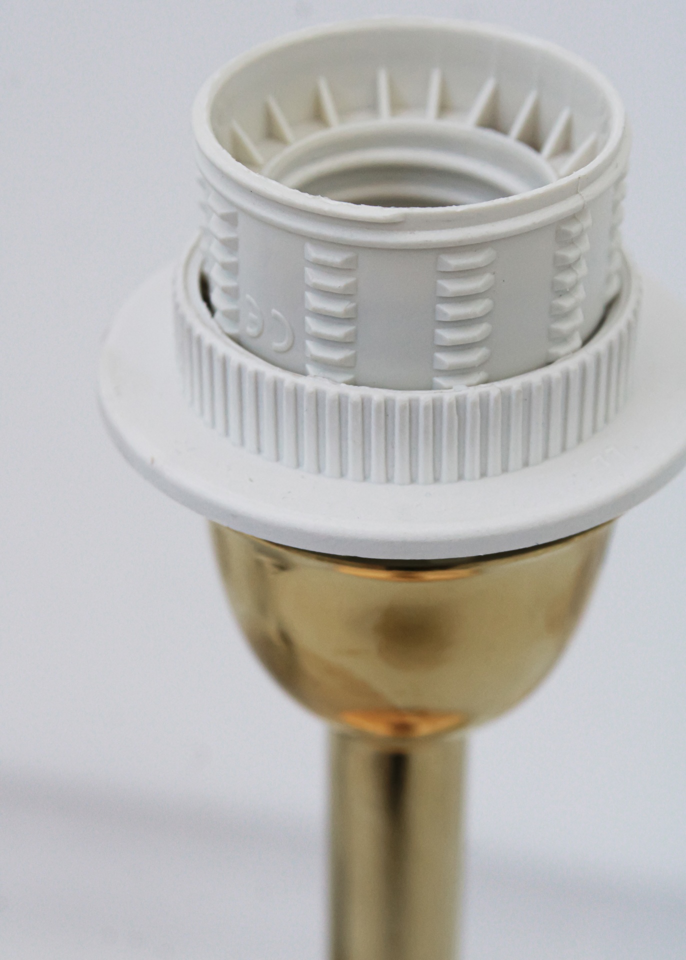 Suporte de lâmpada metálico dourado com parte superior em plástico branco texturizado