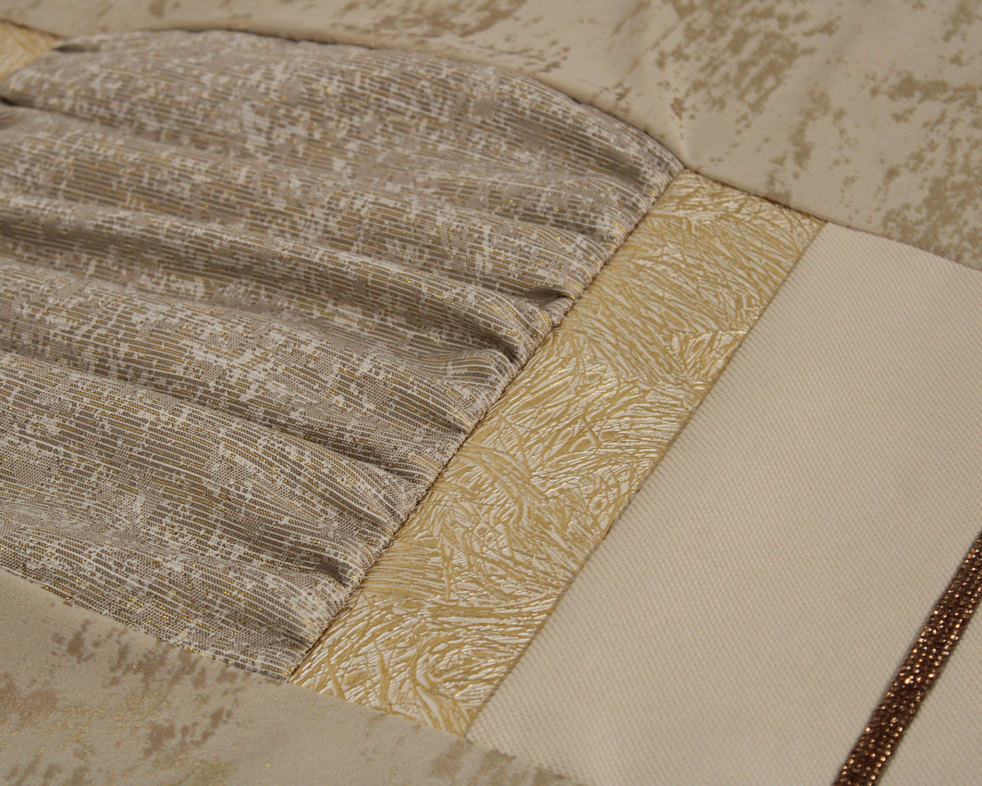 Almofada em tecidos bege, dourado e branco com texturas distintas